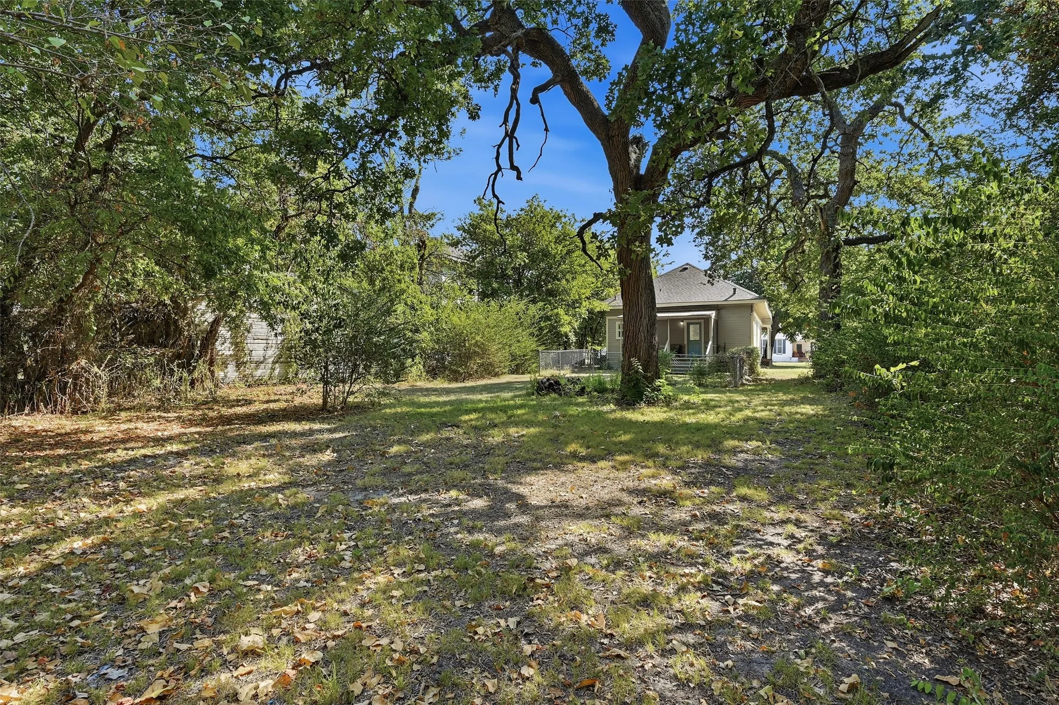 Expansive outdoor space featuring mature trees and a partial exterior of the residence