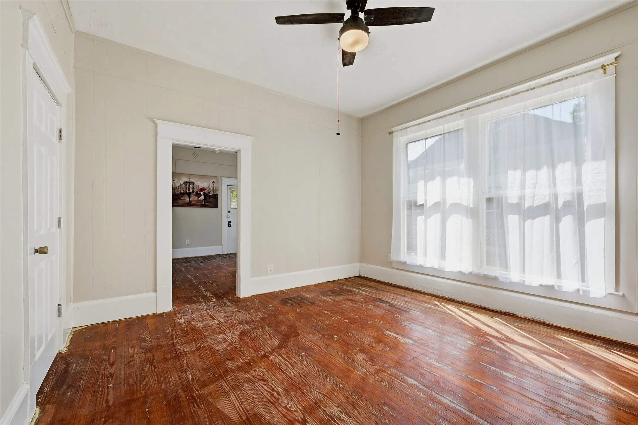 Wood-finish flooring, white trim, and a ceiling fan with light fixture