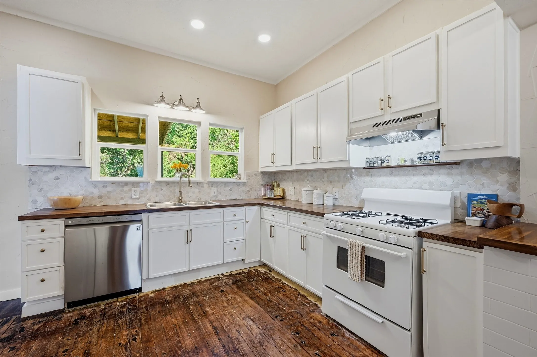 Kitchen featuring white cabinetry, dark wood-finish countertops, stainless steel dishwasher, white gas range, and wood-finish flooring