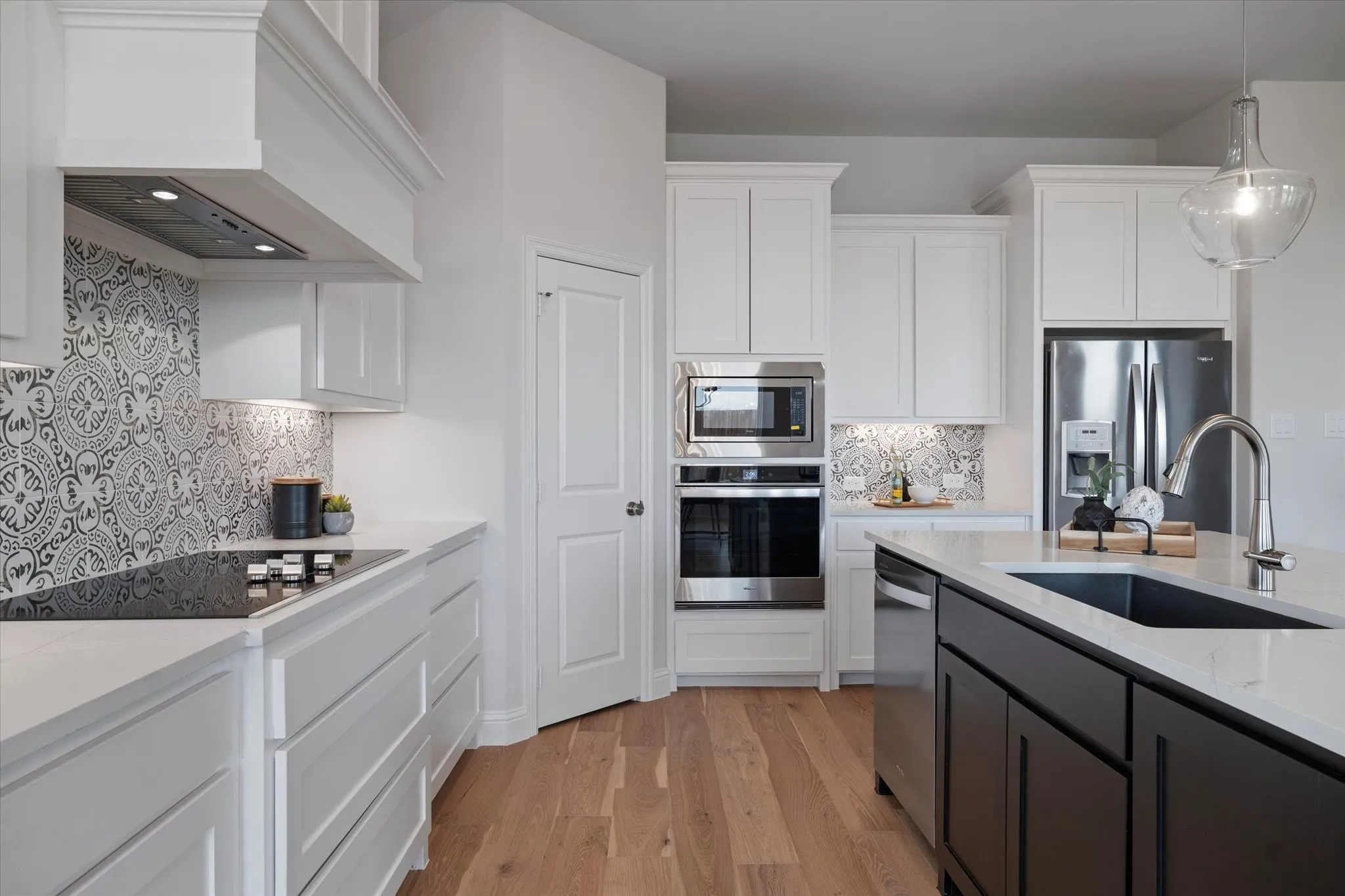 White shaker-style cabinetry with crown molding, stainless steel appliances, solid surface countertops, patterned tile backsplash, and wood-finish flooring