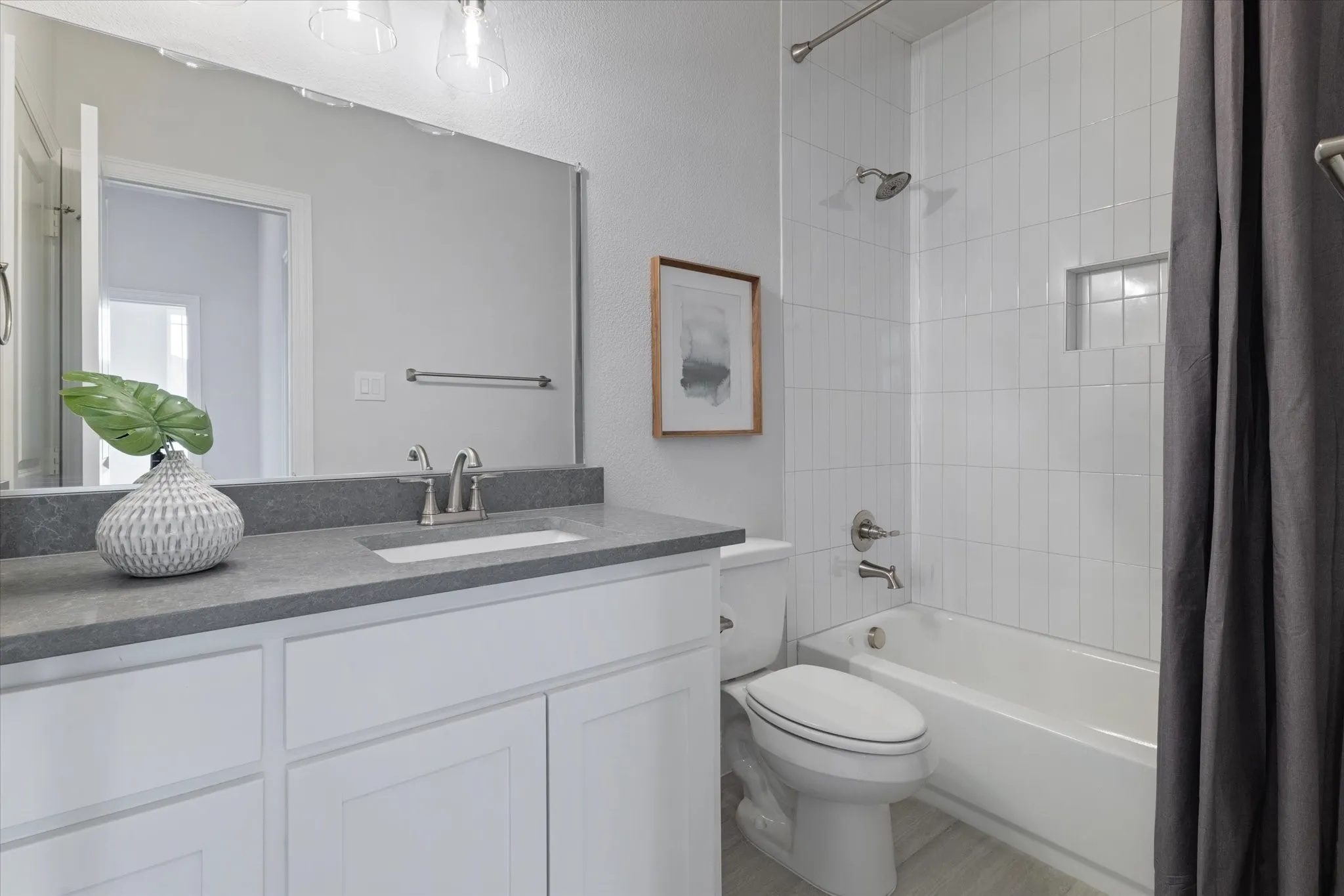 White vanity with a single basin sink, gray countertop, and brushed nickel faucet