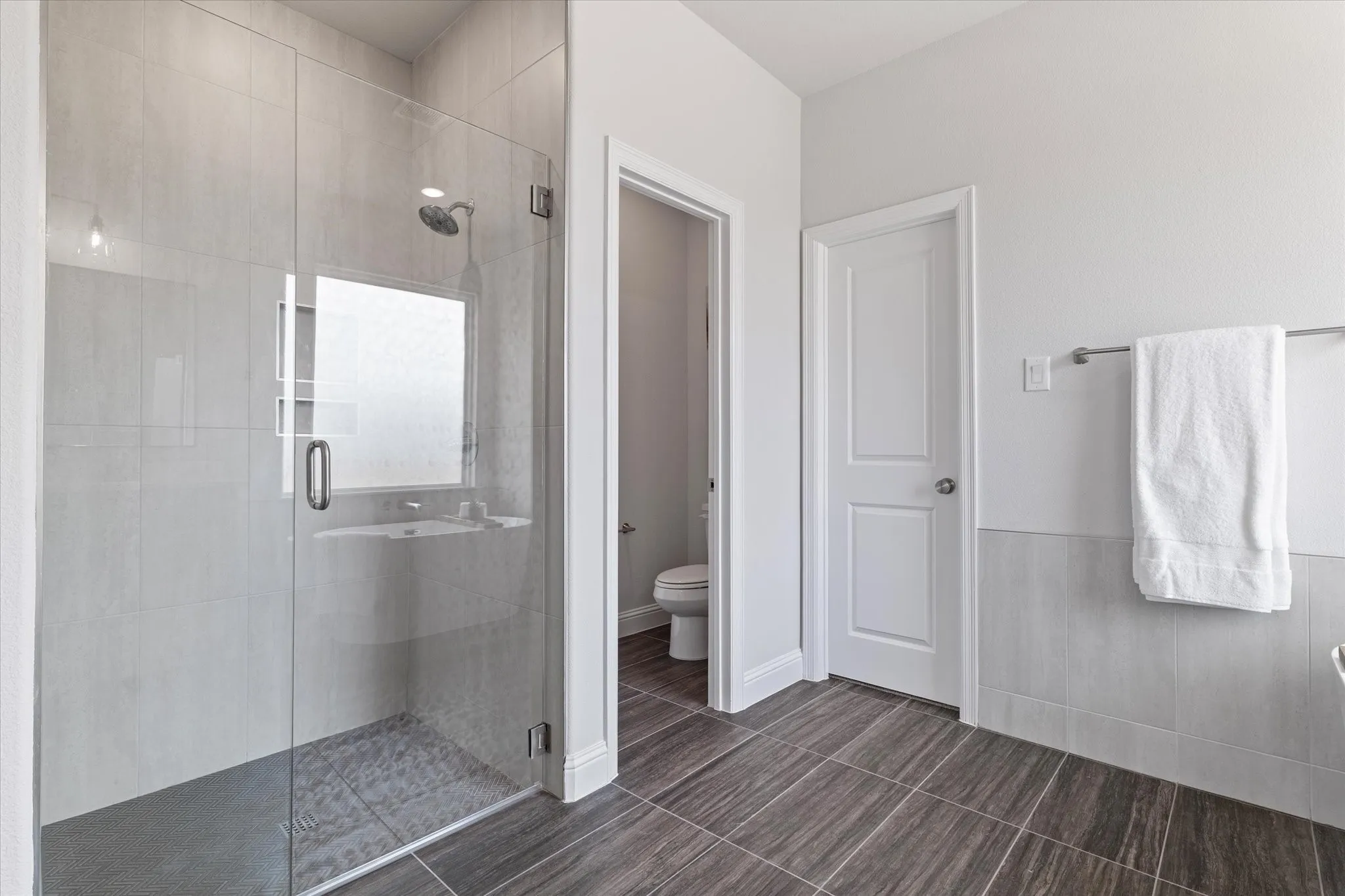 Walk-in shower with clear glass enclosure and light-toned tile surround