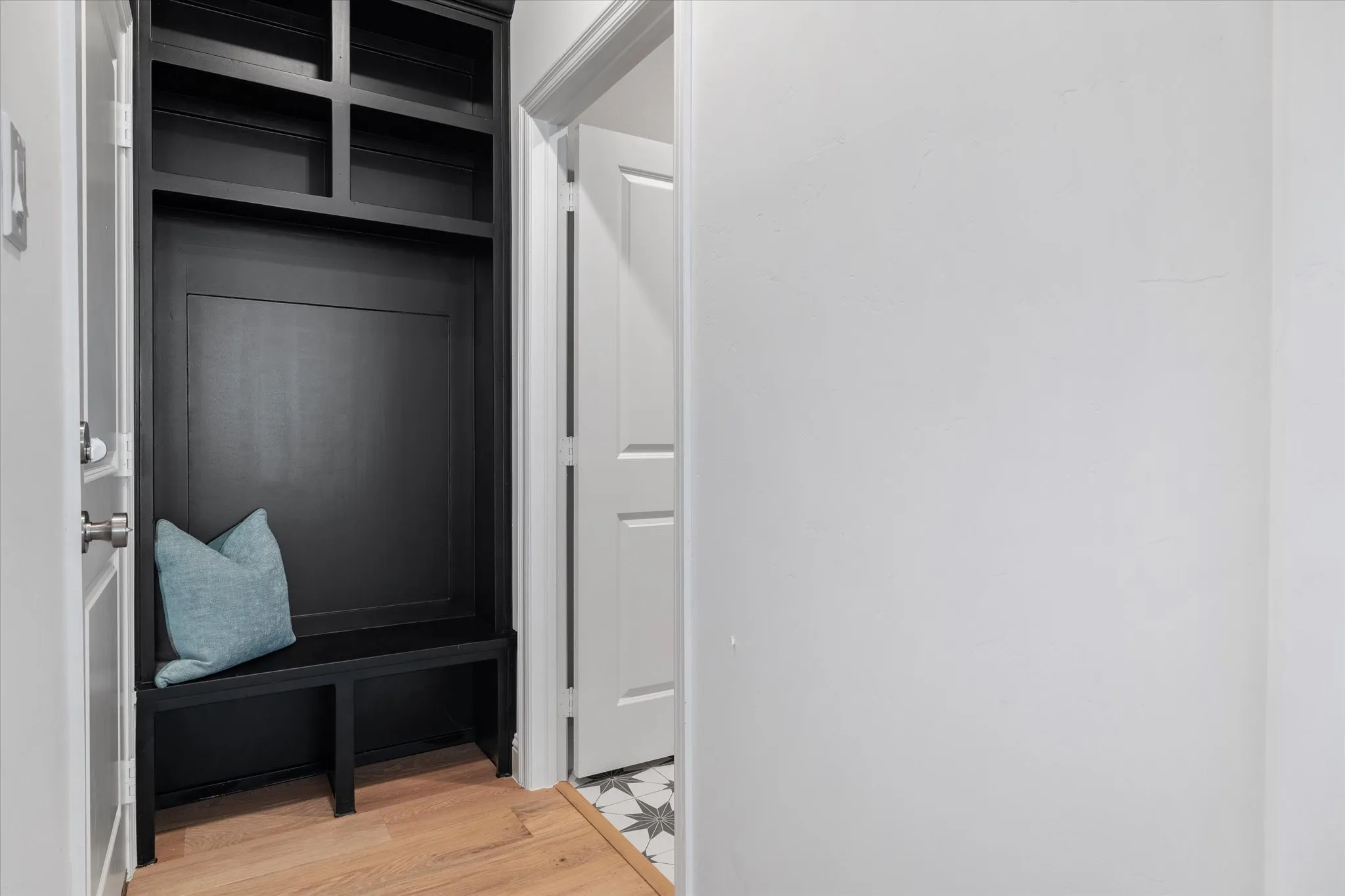 Built-in custom cabinetry with a bench seat and open shelving, wood-finish flooring, and a white interior door