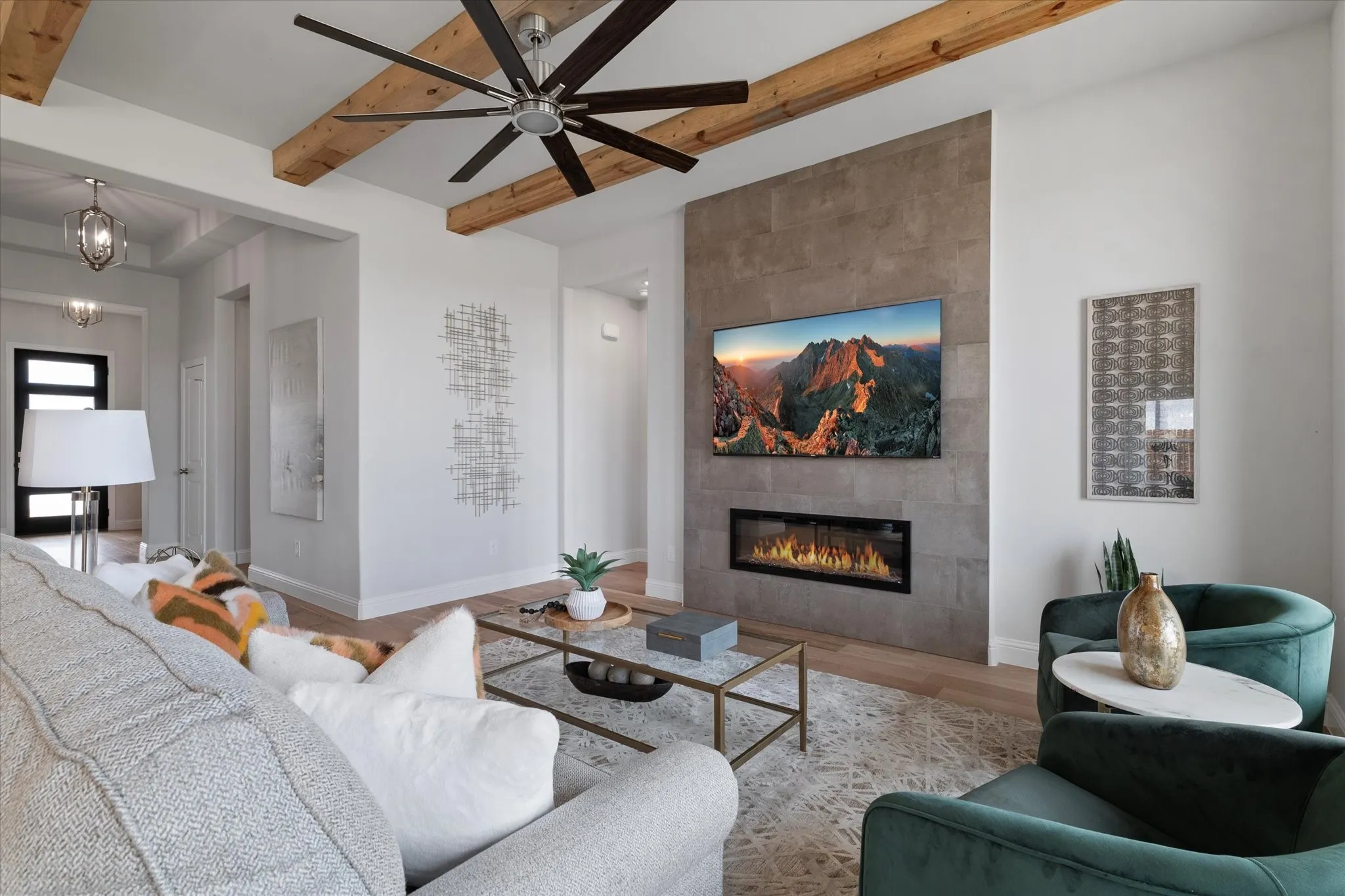 Living area featuring wood flooring, exposed ceiling beams, and a fireplace with a stone-finish surround