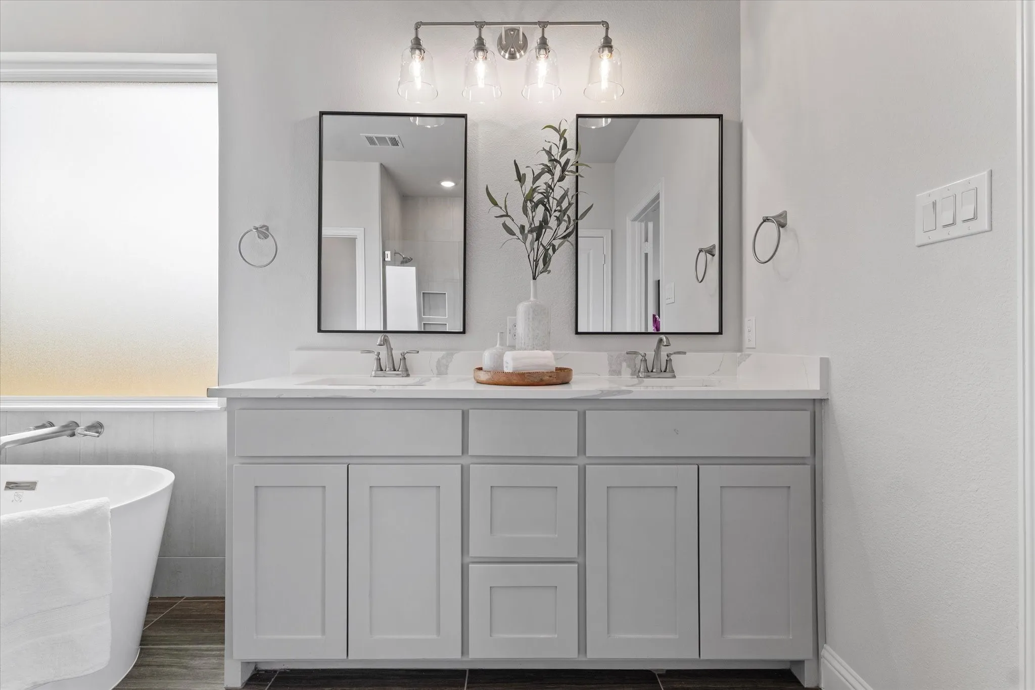 Double vanity with light gray shaker cabinetry, dual rectangular undermount sinks, and stone-finish countertops