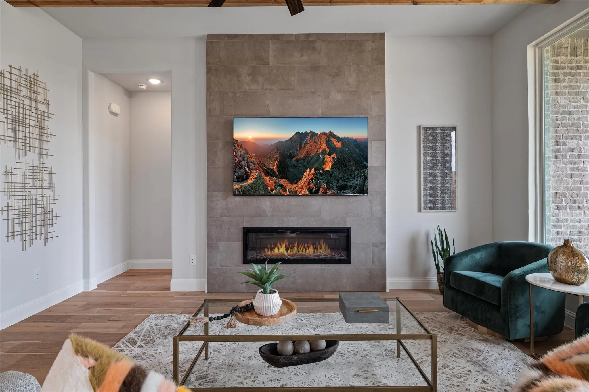 Wood flooring, recessed lighting, and a linear electric fireplace set into a tile-clad wall