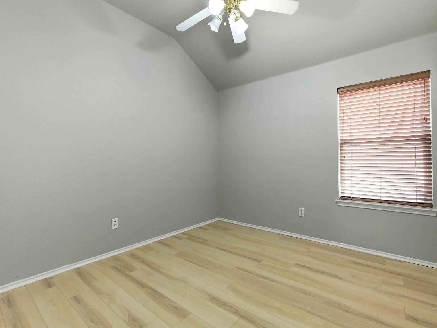 Vaulted ceiling with a ceiling fan, wood-finish flooring, and a single window with blinds
