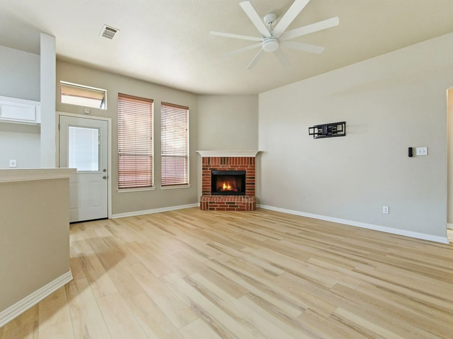 Vaulted ceiling, ceiling fan, wood-finish flooring, brick fireplace, and built-in cabinetry