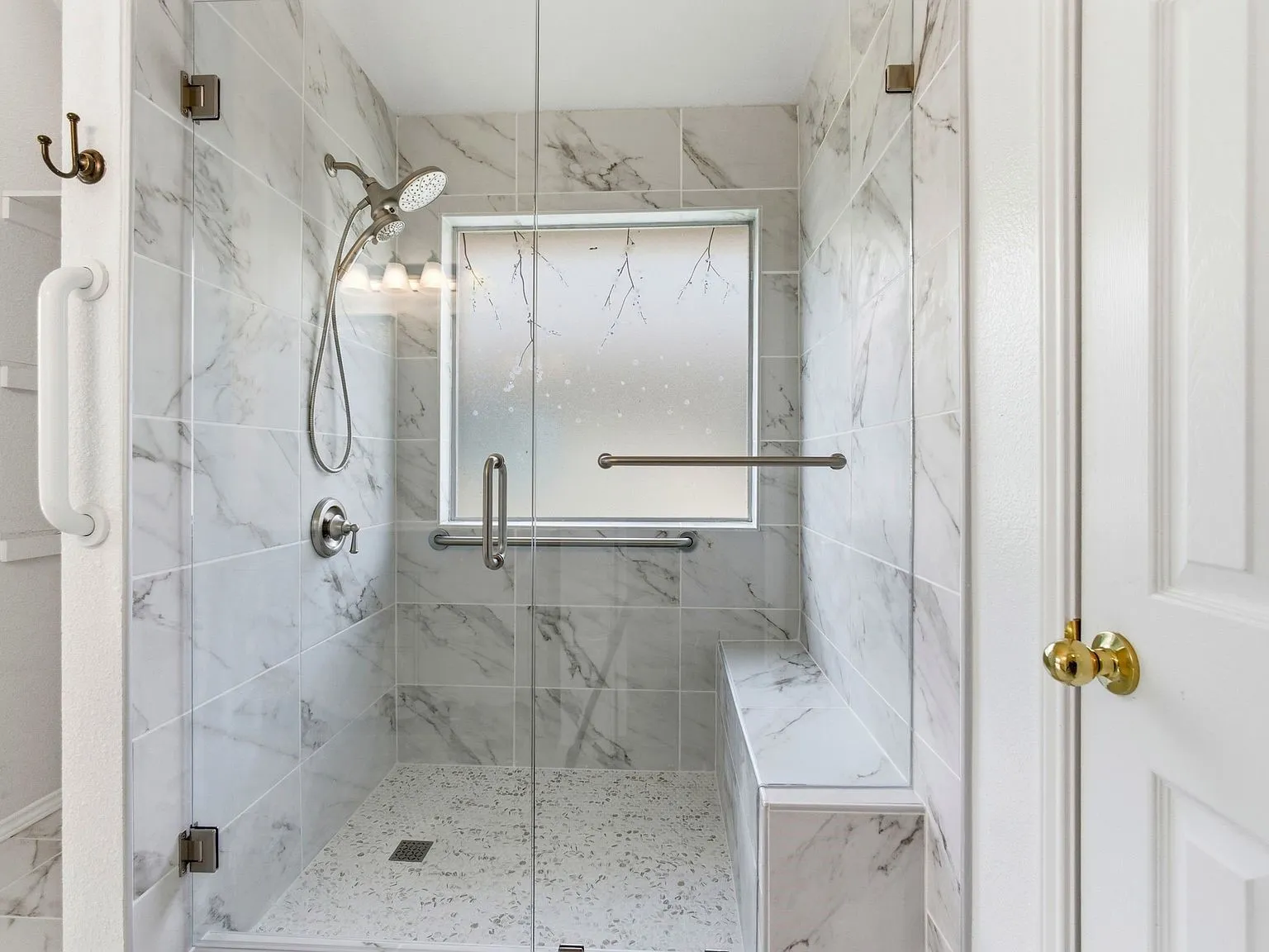 Walk-in shower with full-height tile surround, built-in bench, and glass enclosure