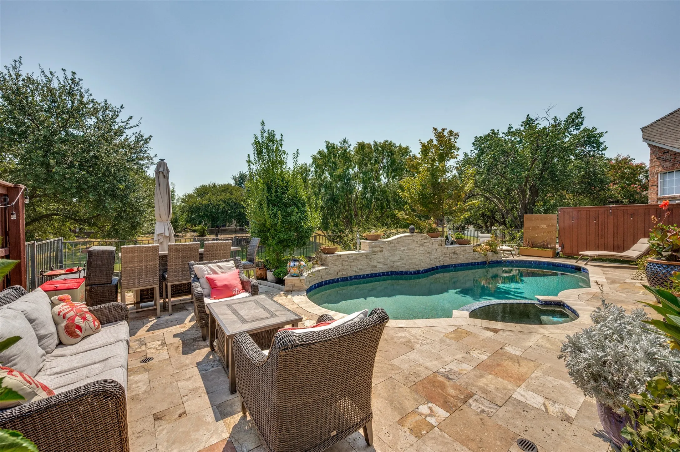 Large Stone tile patio with a sparkling pool and integrated spa