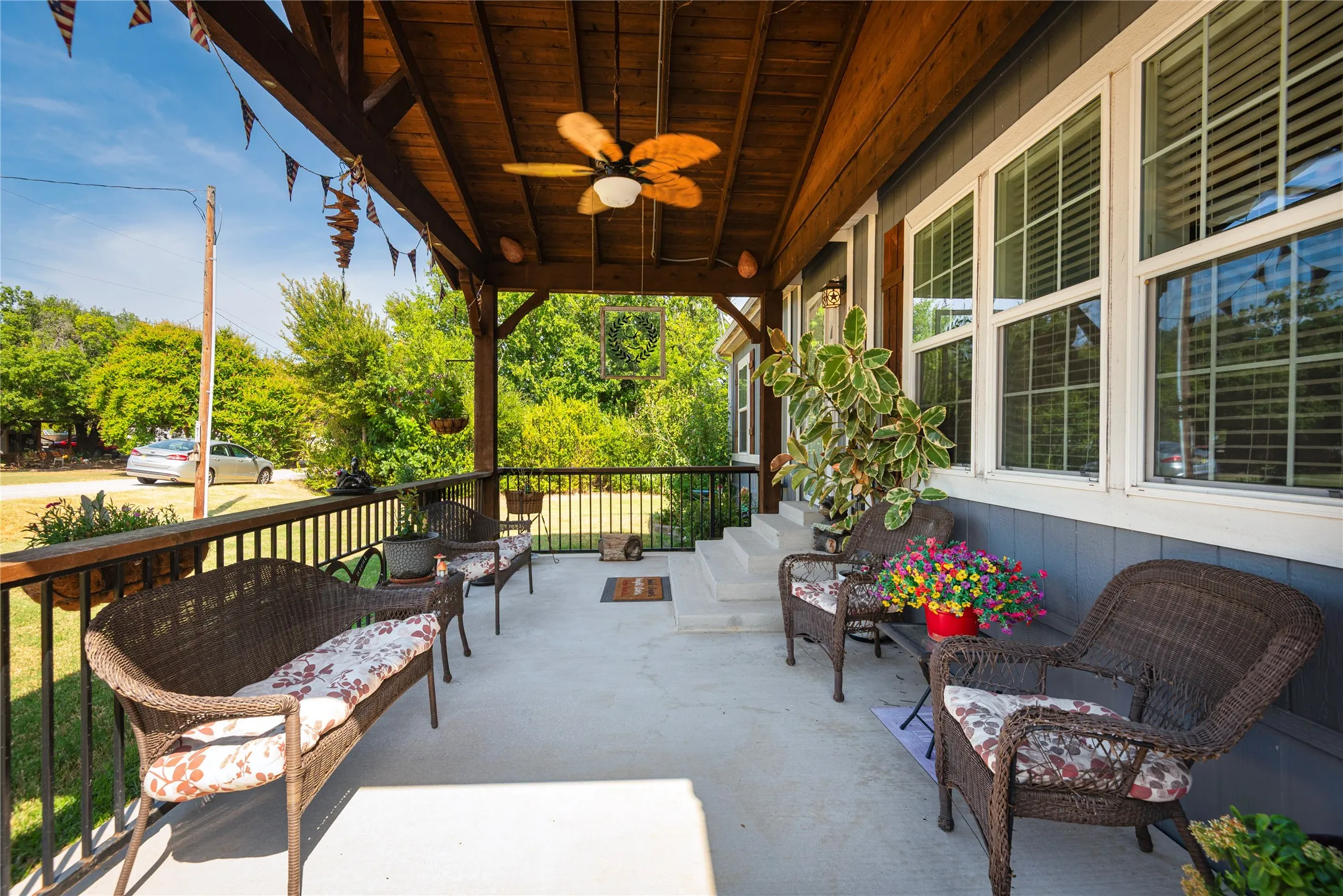Covered porch with wood-finish ceiling, ceiling fan, and white window frames