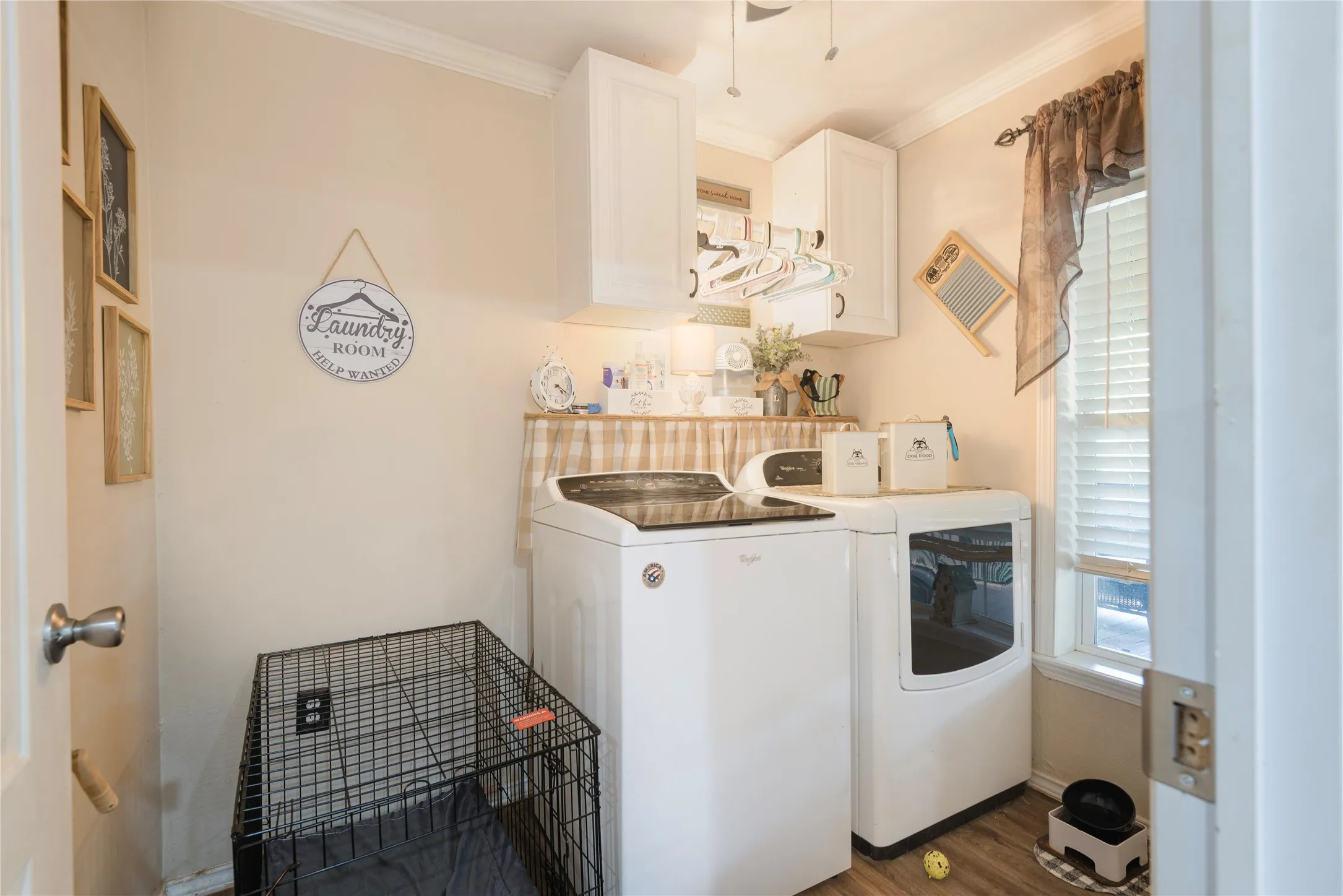 Laundry area featuring wood-finish flooring, white cabinetry, and natural light