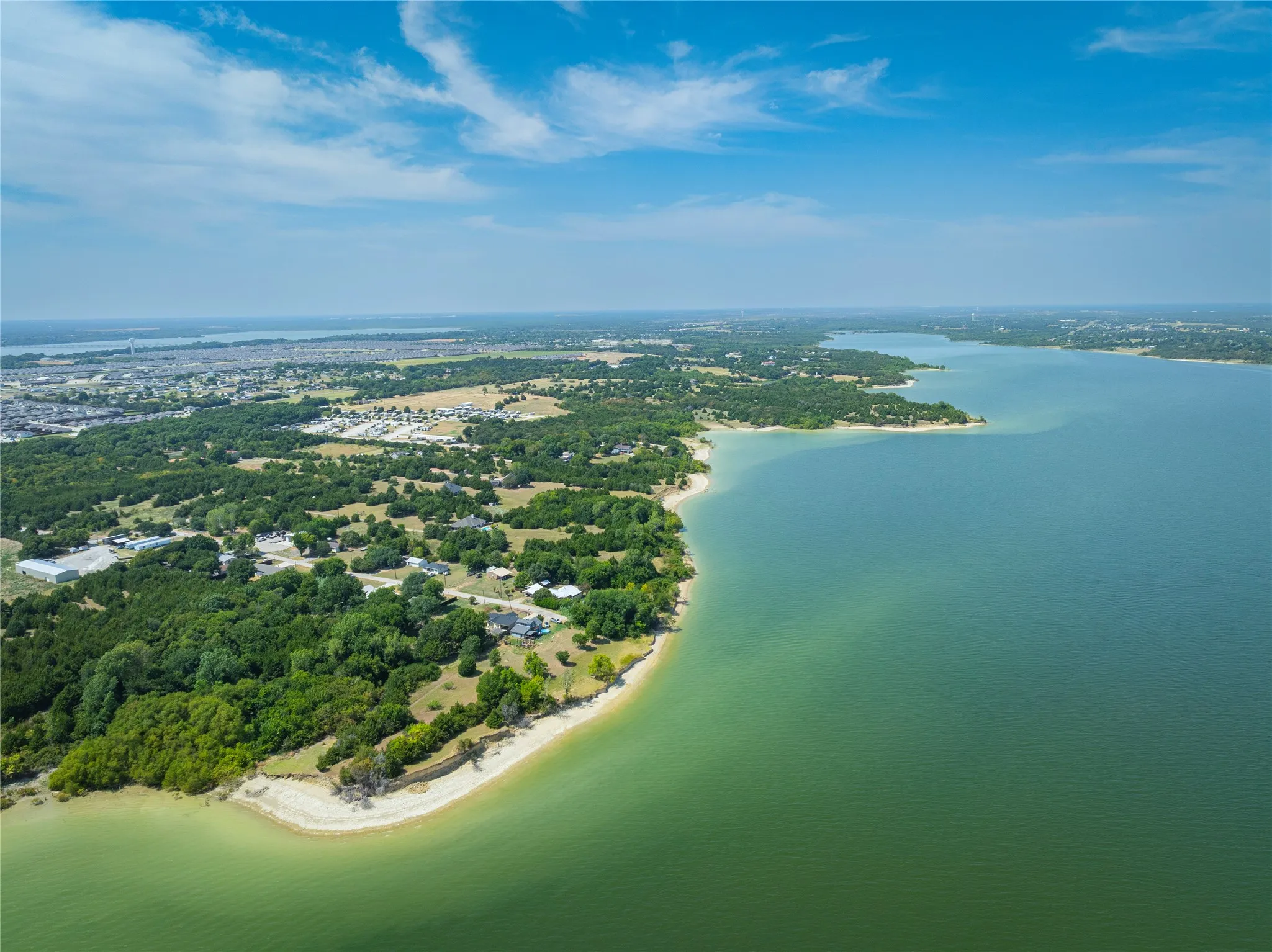 Expansive waterfront property with a natural shoreline and mature tree coverage, offering direct access to a large body of water