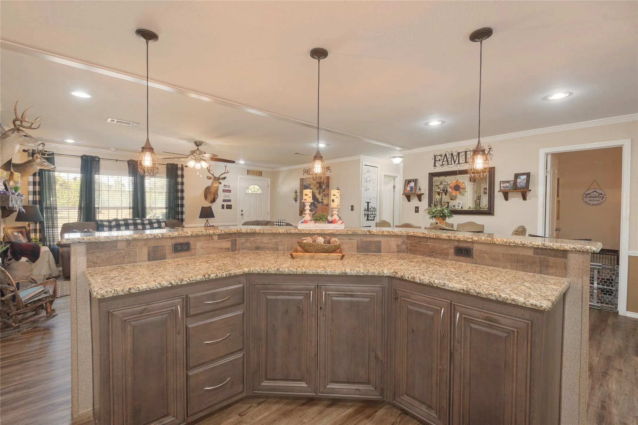 Kitchen island with stone-finish countertops, wood-finish base cabinetry, and three pendant lights