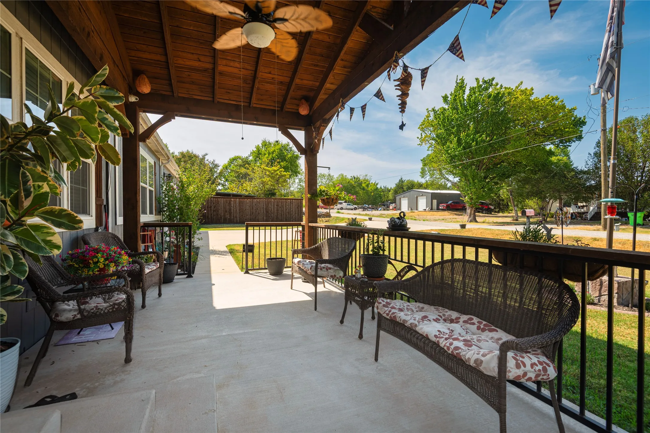 Covered front porch with a wood-finish ceiling, ceiling fan, and wrought iron railings