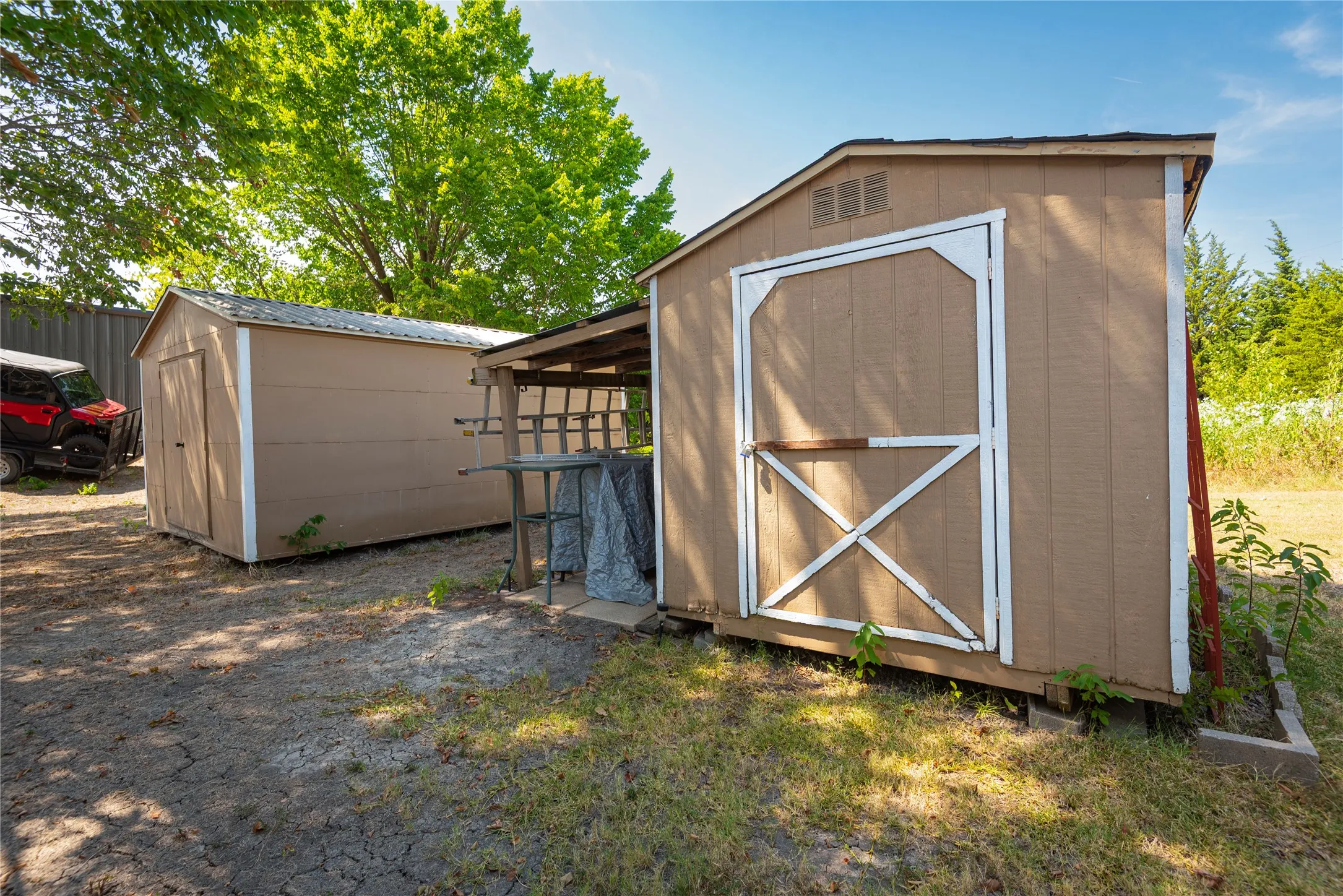 Two shed structures with neutral-toned siding, white trim, and pitched roofs