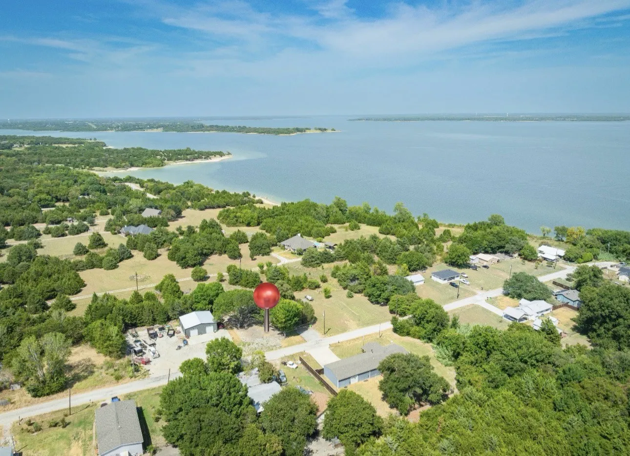 Aerial perspective featuring a waterfront setting, surrounded by mature trees and varied terrain