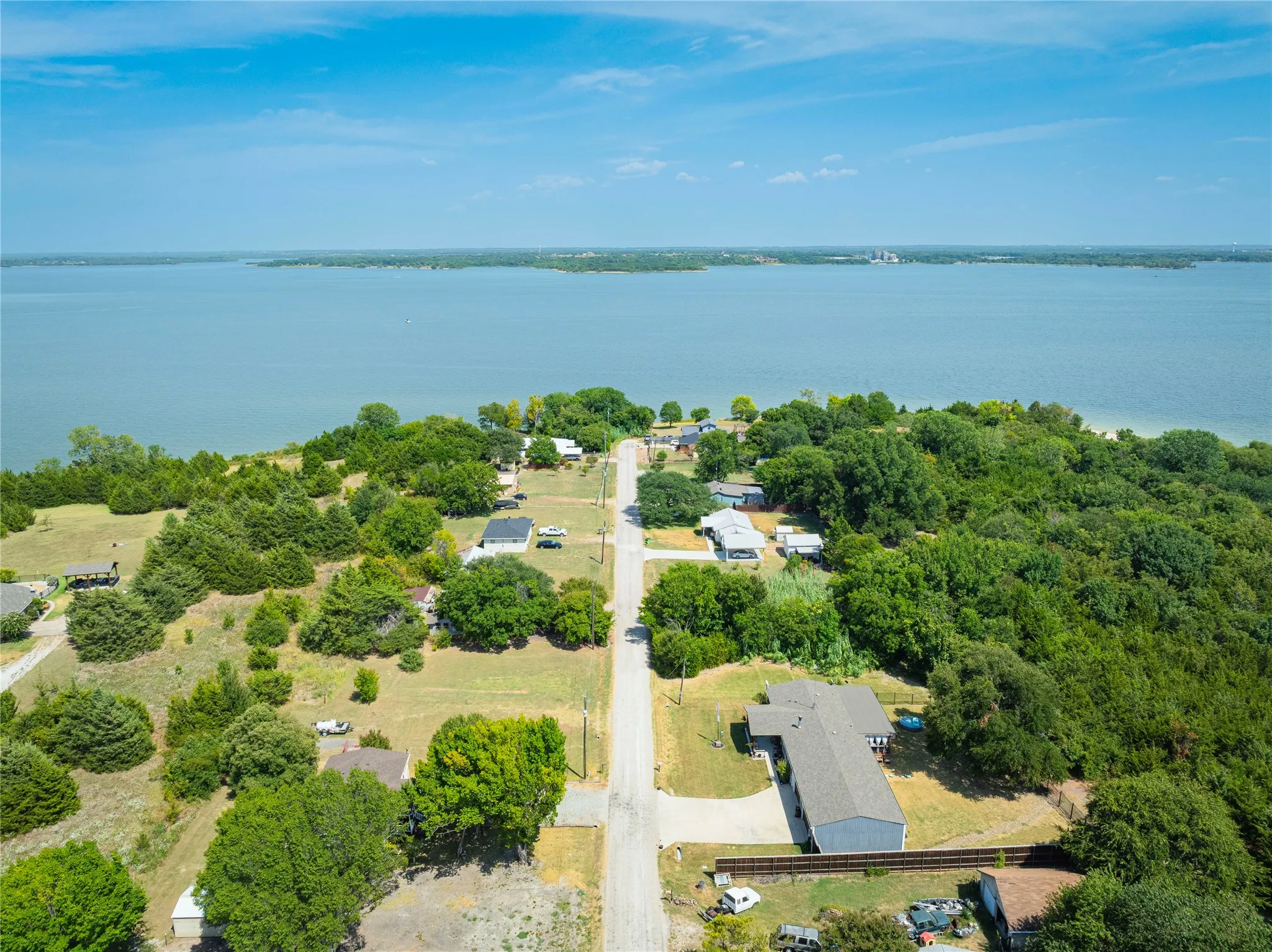 Expansive lakefront property featuring a clear blue lake, established trees, and a developed road system