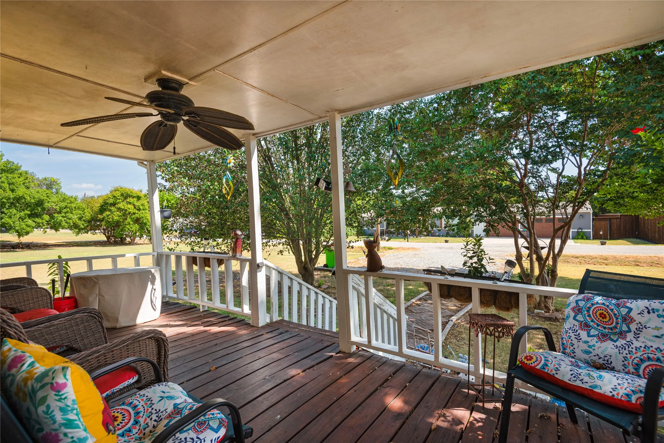 Covered porch featuring a ceiling fan, wood-finish flooring, and white railings