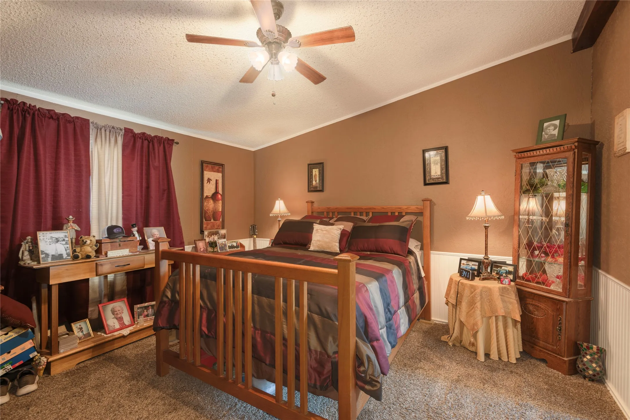 Carpeted room featuring a ceiling fan, crown molding, and wainscoting