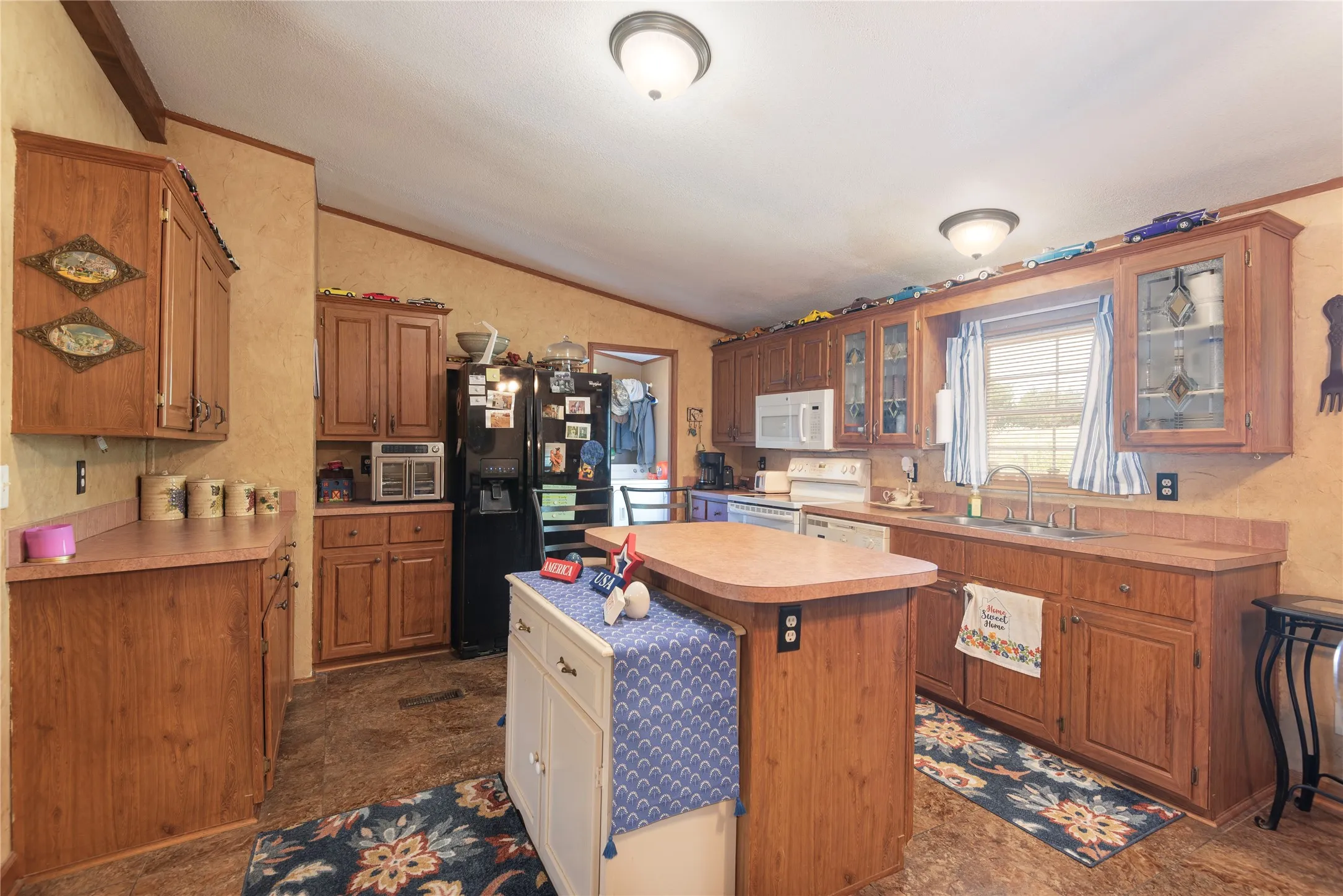 Kitchen featuring wood-finish cabinetry, a central island with a built-in breakfast bar, a double basin sink, and wood-finish countertops
