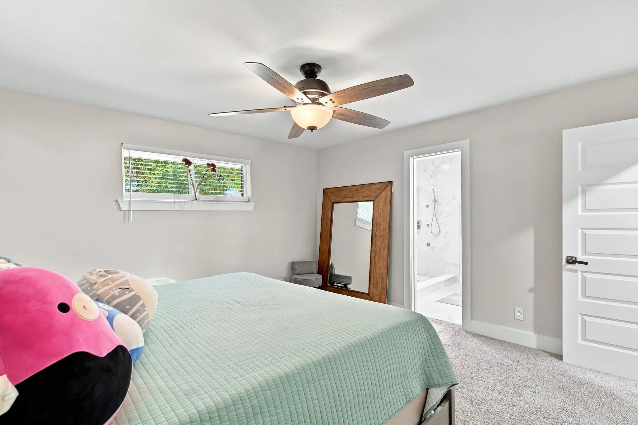 Recessed window with blinds, ceiling fan with integrated lighting, plank-style interior door, and soft grey carpeting