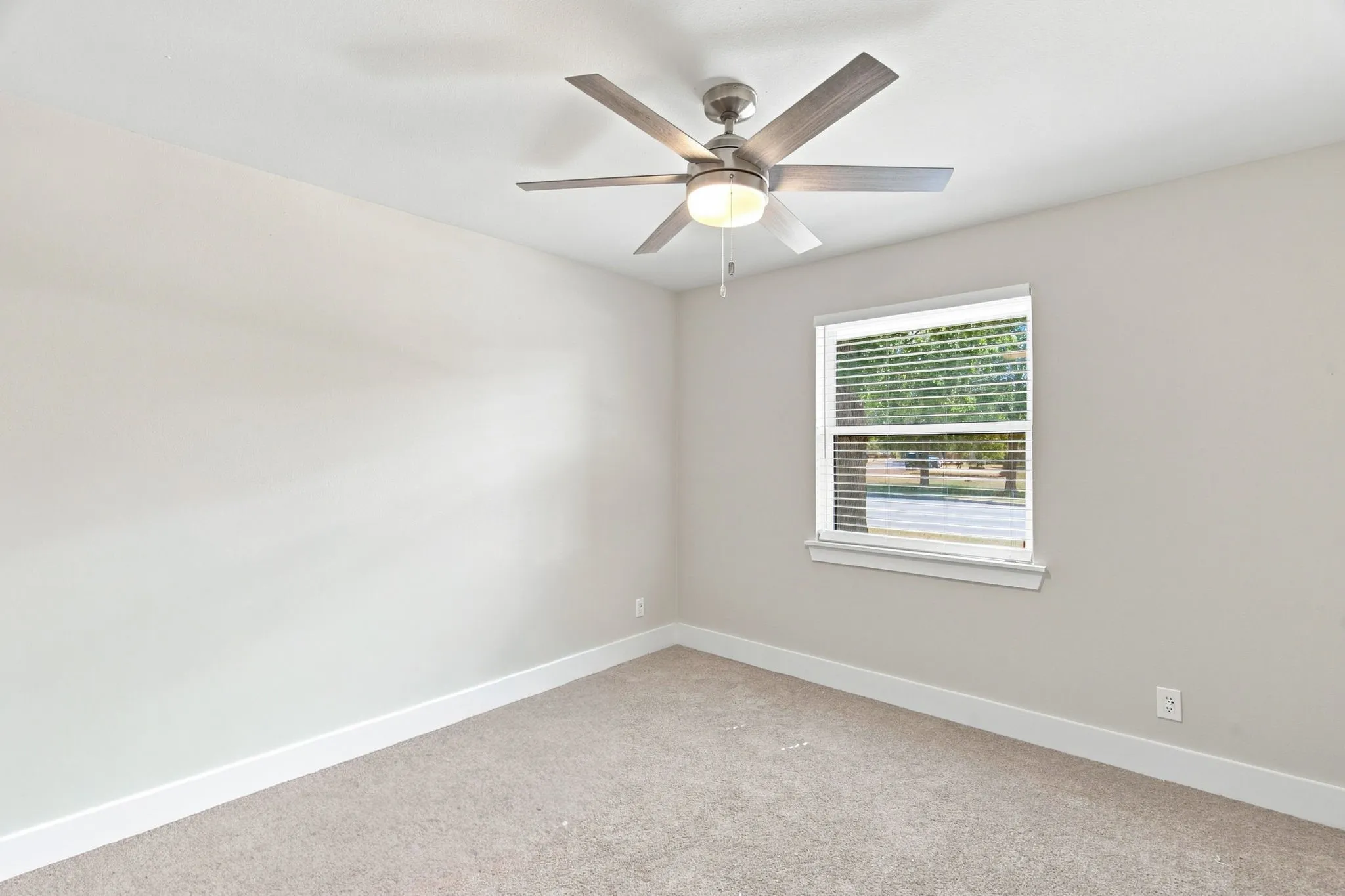 Neutral wall paint, ceiling fan with integrated lighting, window with blinds, and carpeting