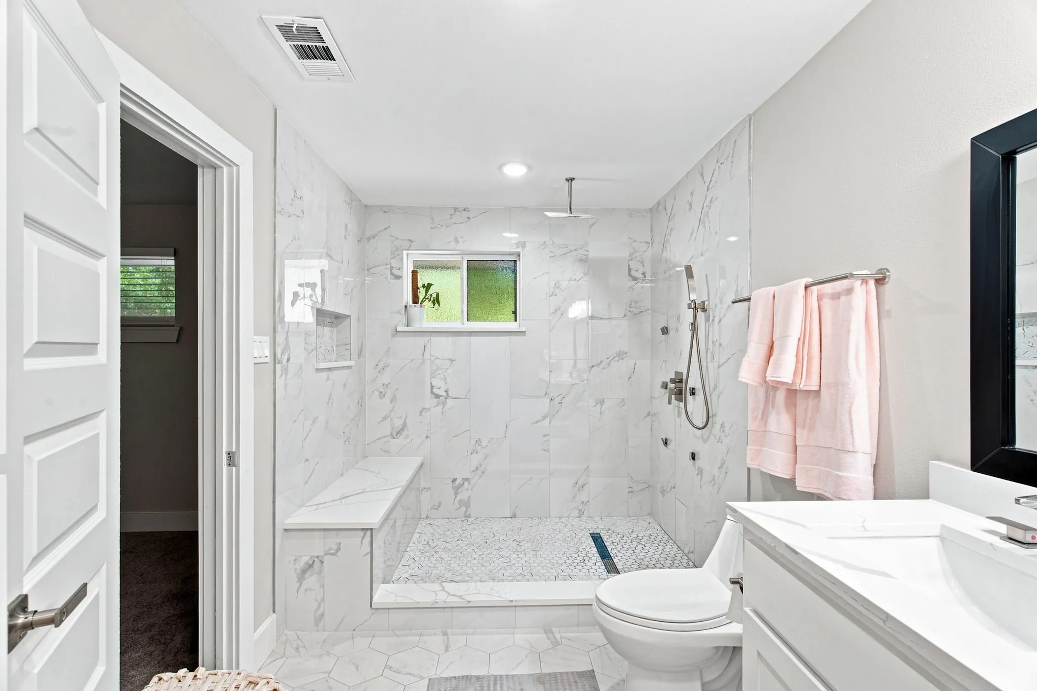 Shower with full wall tile surround, rain shower head, handheld shower, and built-in bench