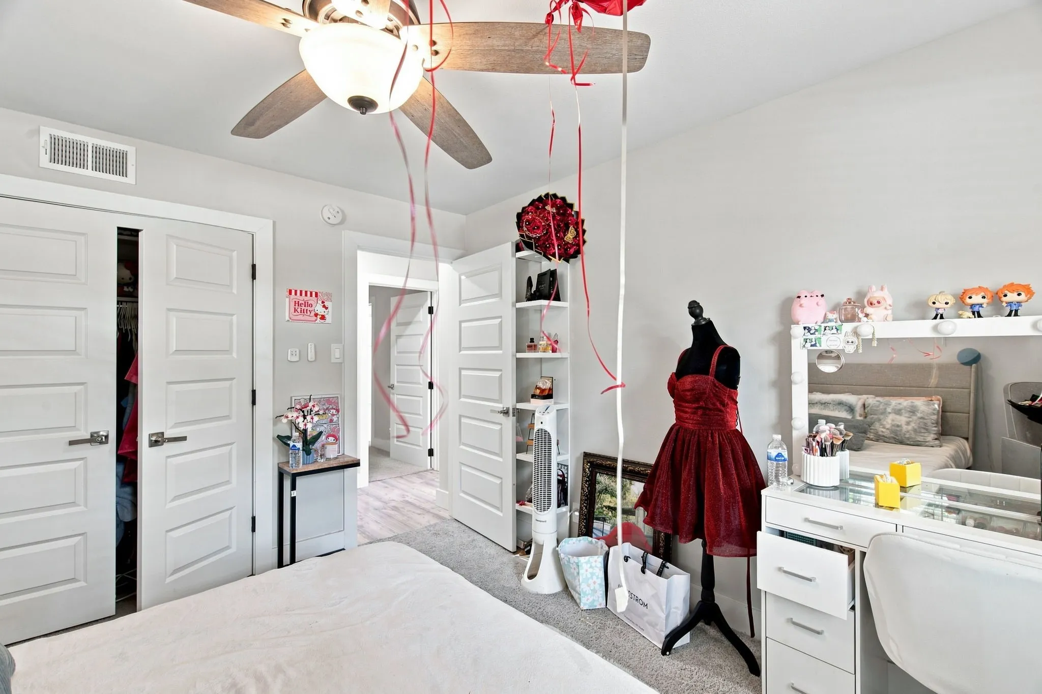 Bright bedroom suite featuring ceiling fan with light fixture, white double-door closet system, built-in shelving and storage cabinetry, carpet flooring, and recessed ceiling lighting throughout