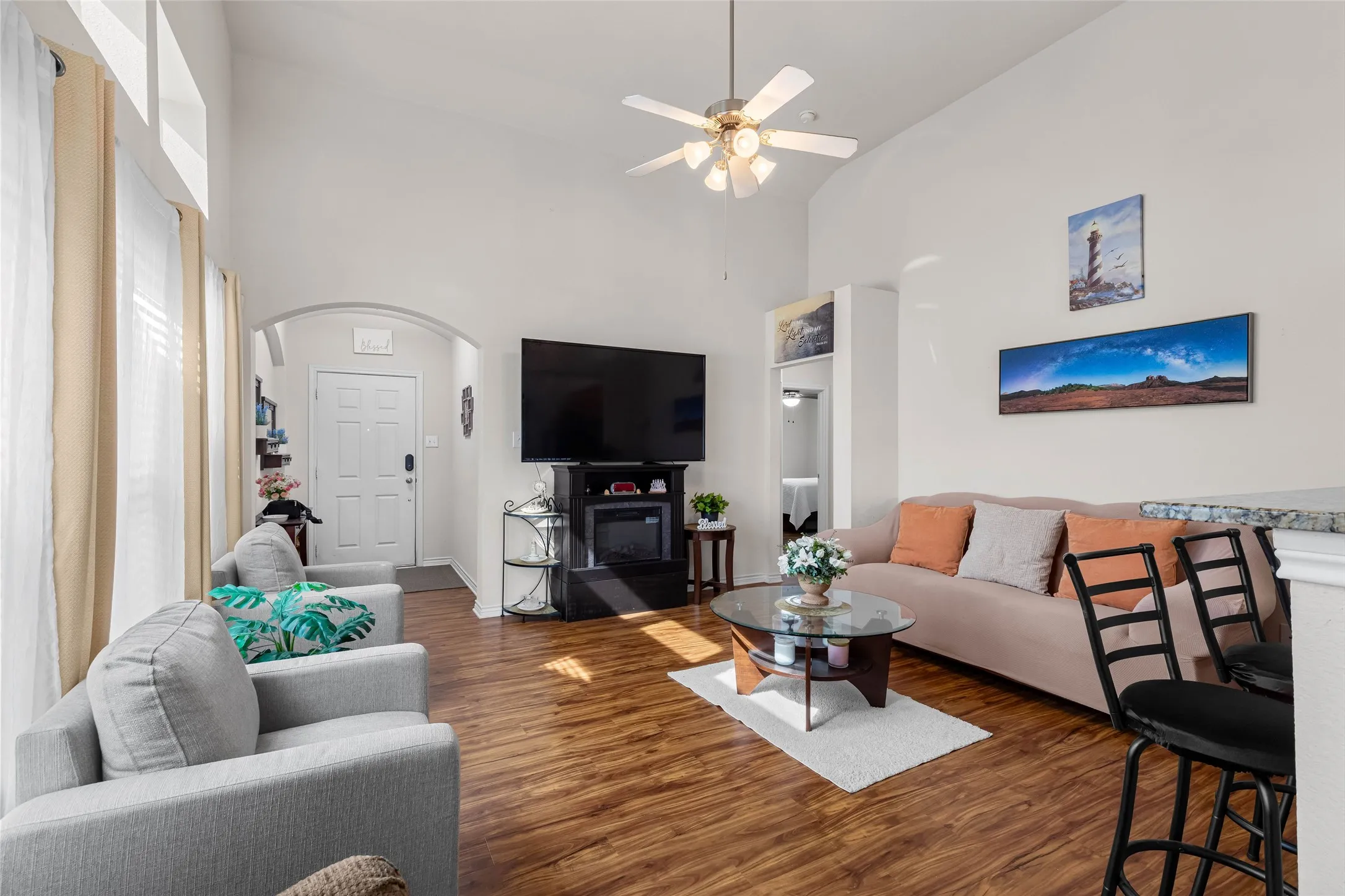 Bright, open living room featuring wood look flooring, recessed ceiling lighting with a ceiling fan and space for relaxing or entertaining.