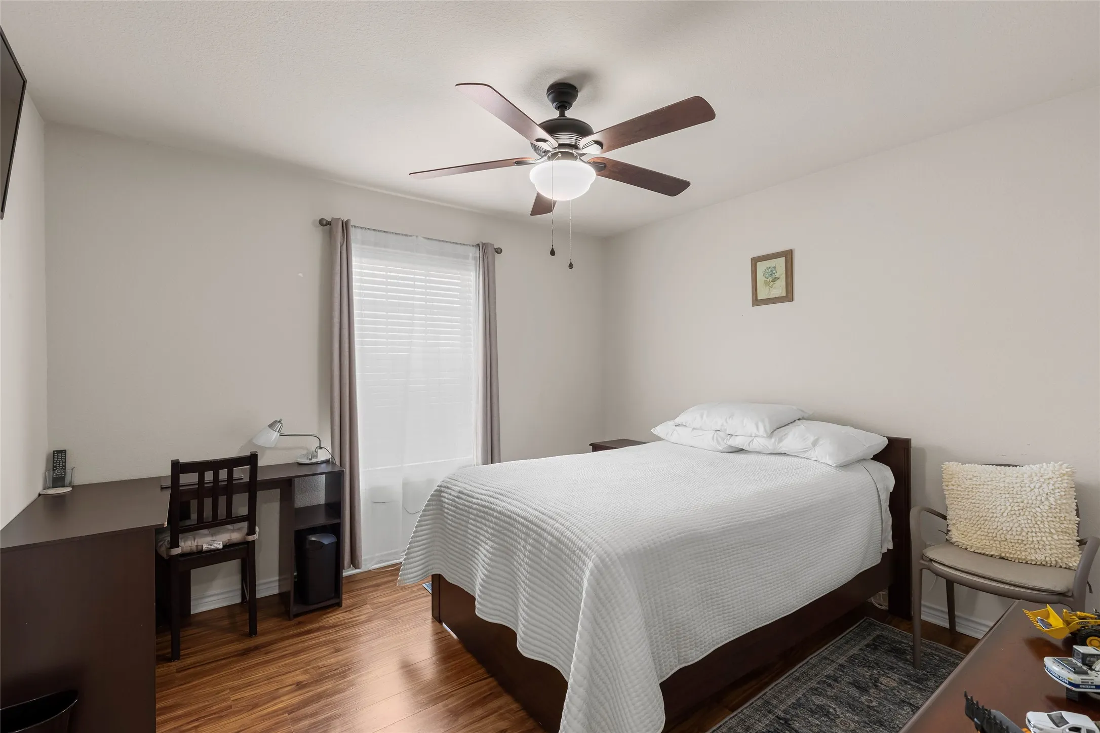 Secondary bedroom offers wood look flooring, large window, ceiling fan, and closet.