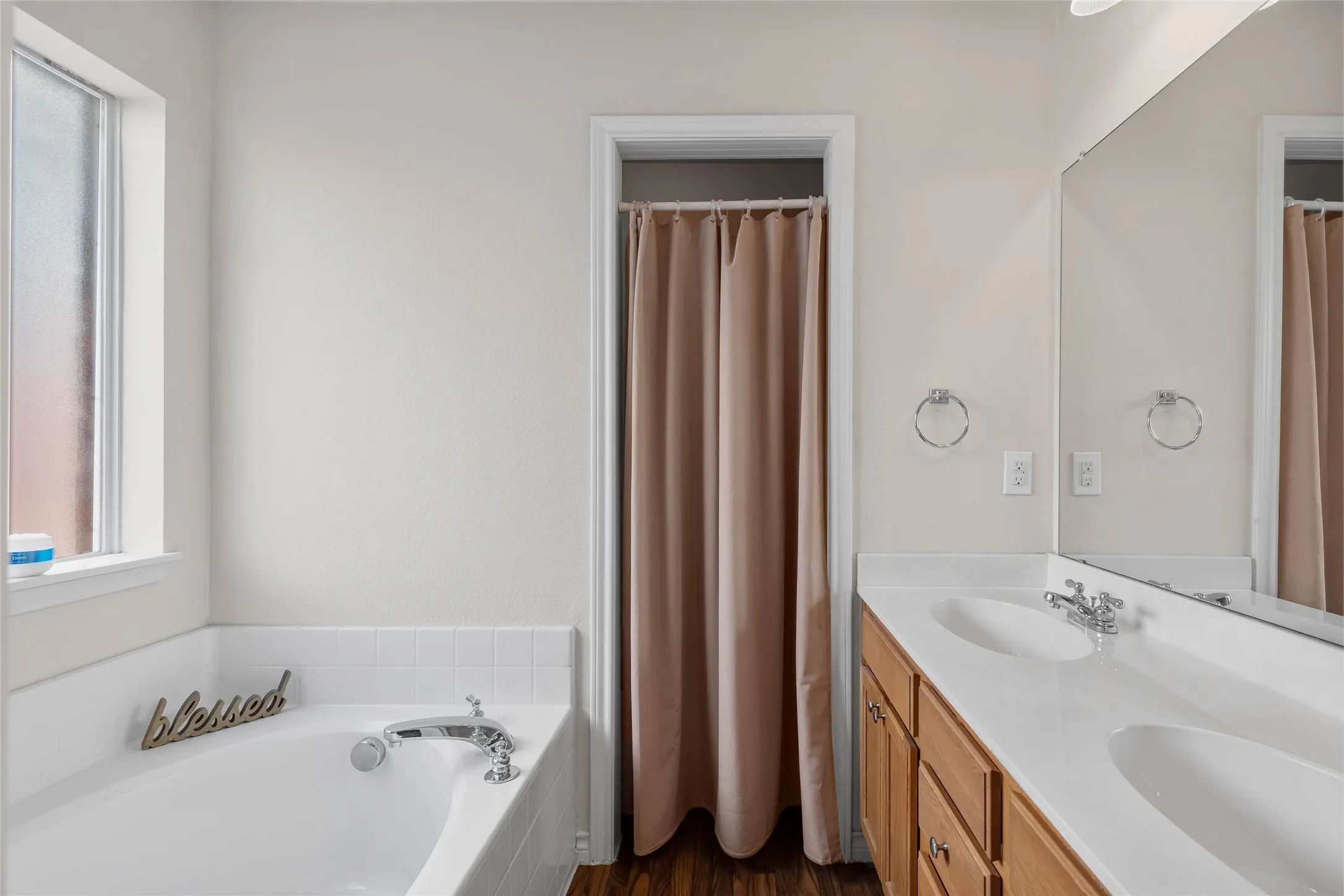 Primary bathroom offers dual sinks, lot of cabinet space, and full size garden tub.