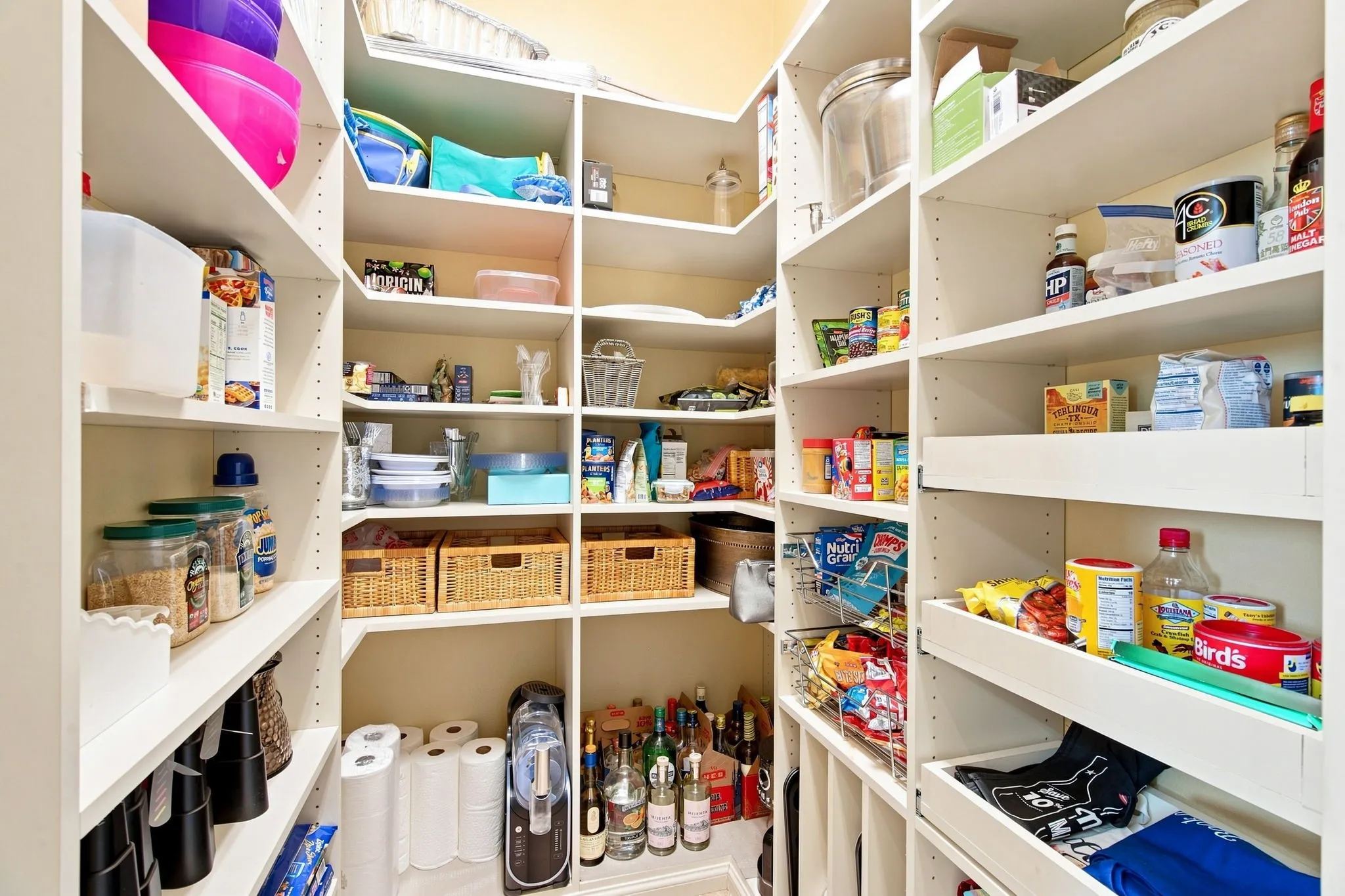 Walk-in pantry featuring extensive white shelving, multiple adjustable shelves, integrated corner shelving, and pull-out drawers