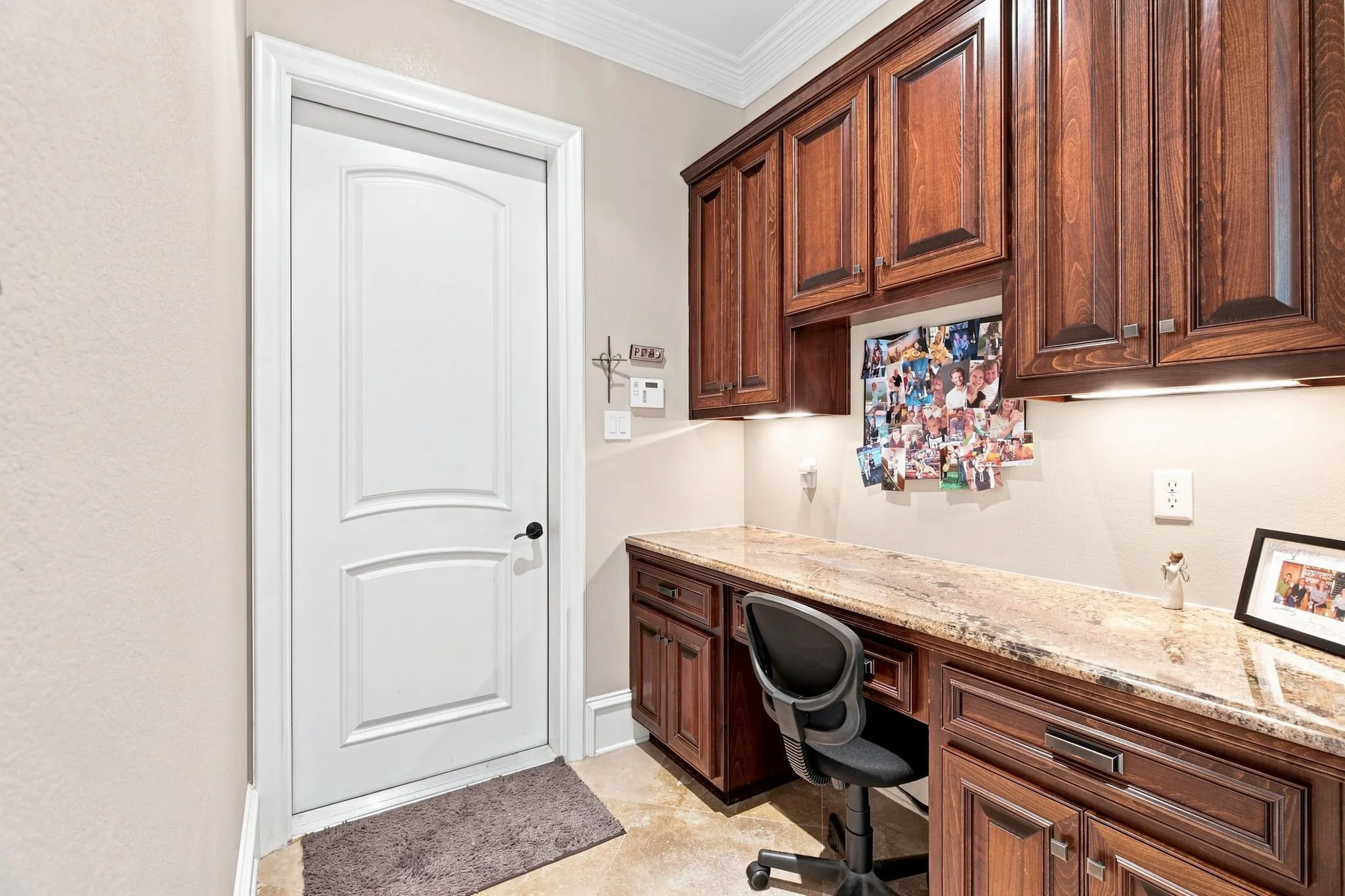 Built-in desk area featuring wood cabinetry, under-cabinet lighting, and a stone countertop