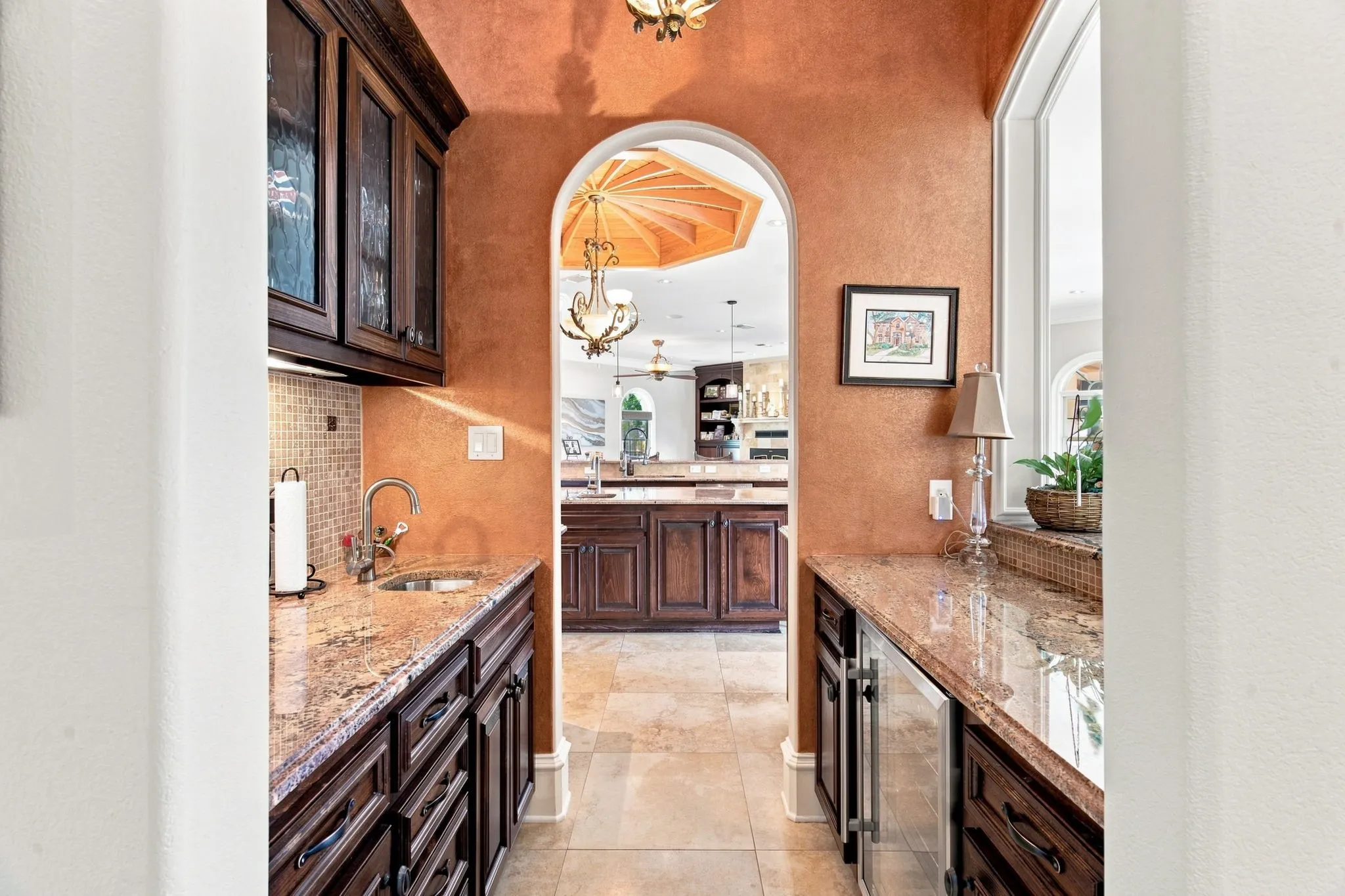 Wet bar featuring granite countertops, dark wood cabinetry, a built-in sink, and a beverage refrigerator