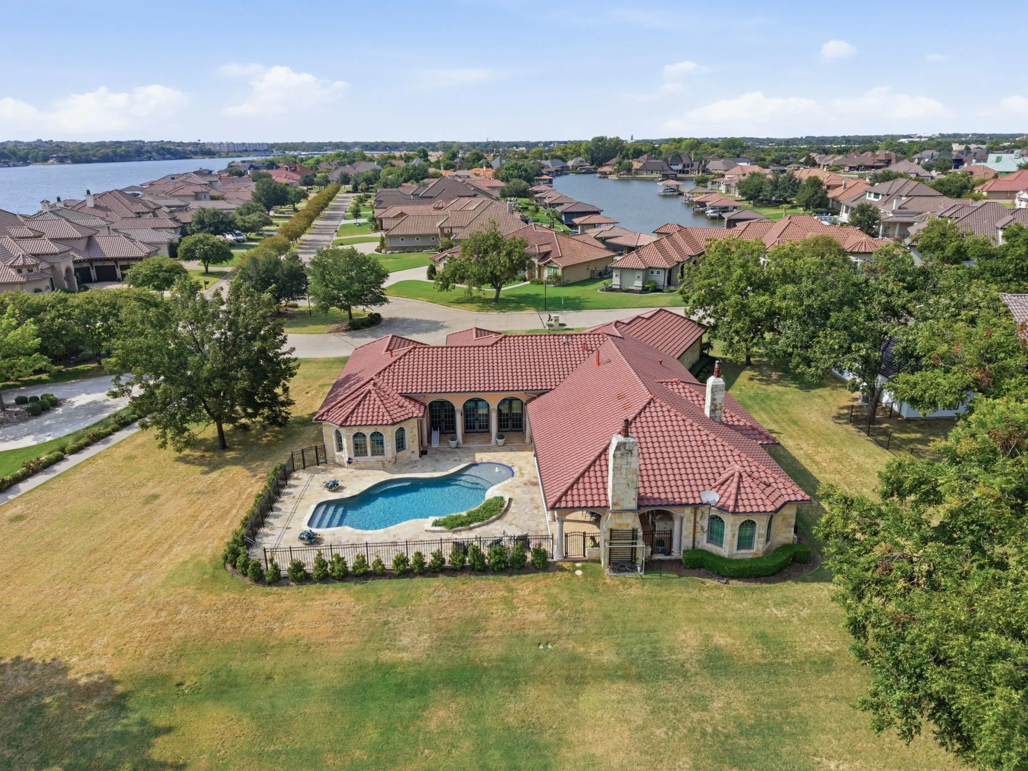 Mediterranean-style residence featuring a red tile roof, an in-ground swimming pool, stone patio, and a stone-clad exterior