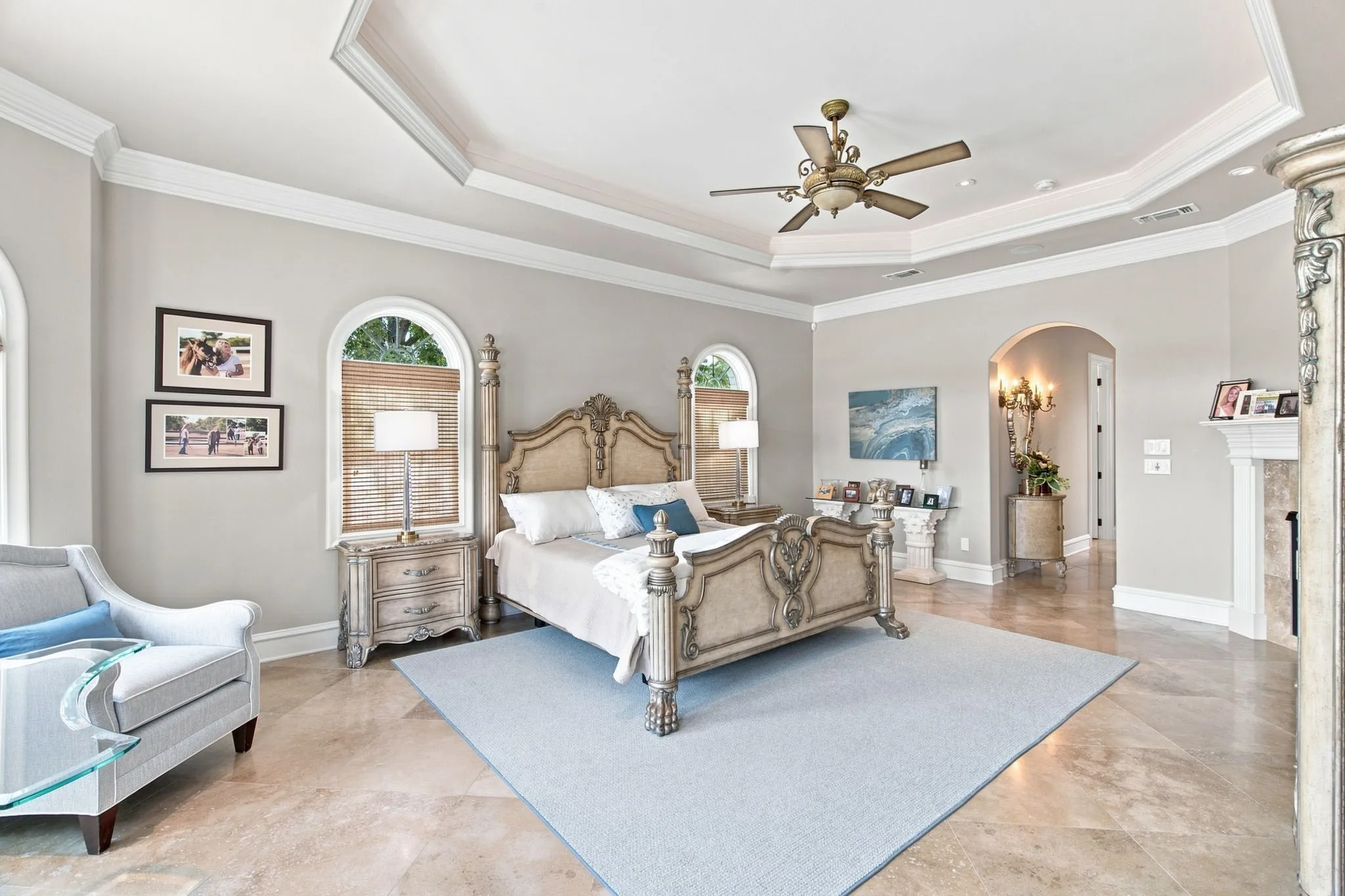 Tray ceiling with crown molding, arched windows, tile flooring, and an arched entry