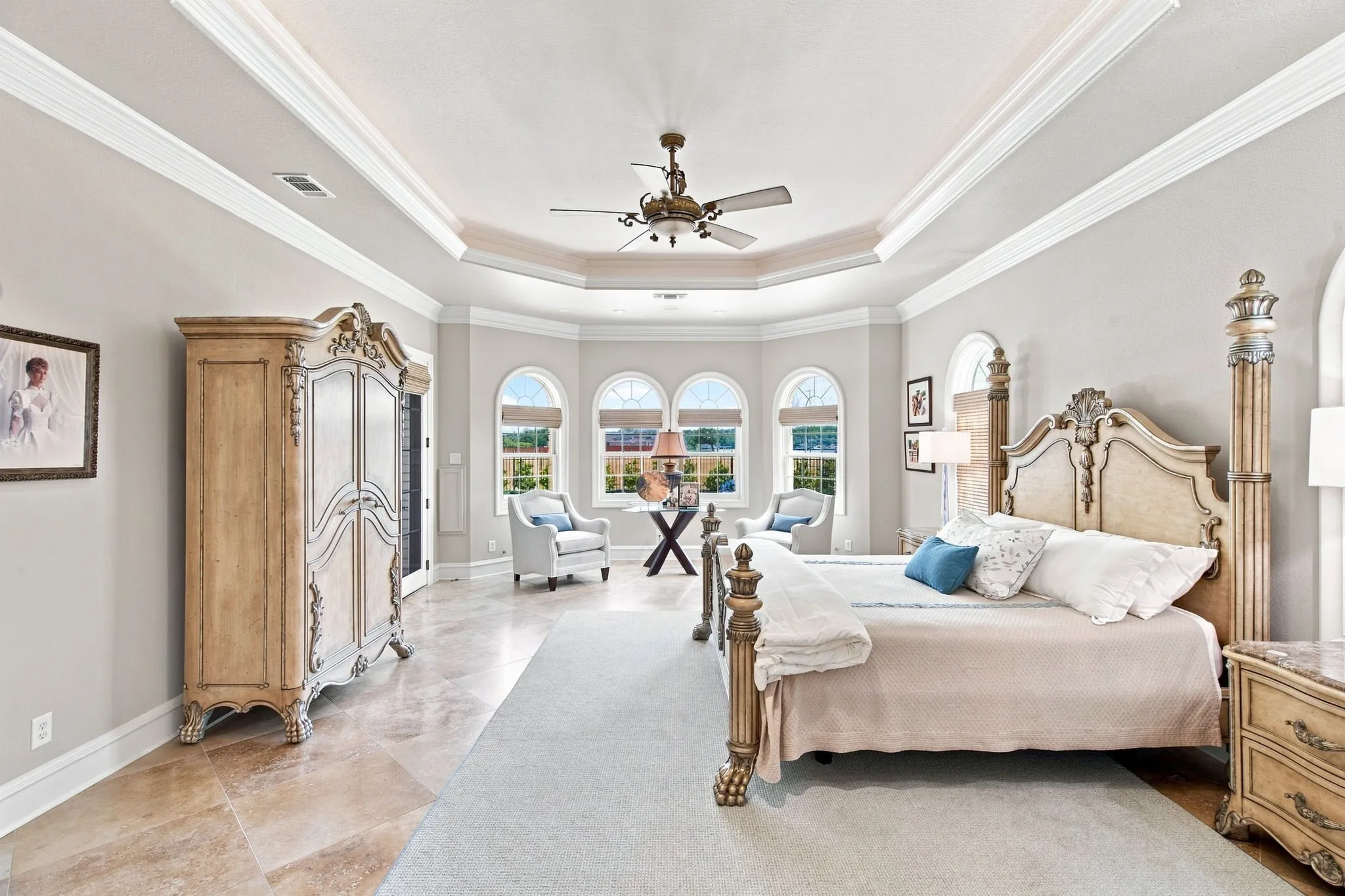 Tray ceiling with crown molding, arched windows, and tile flooring
