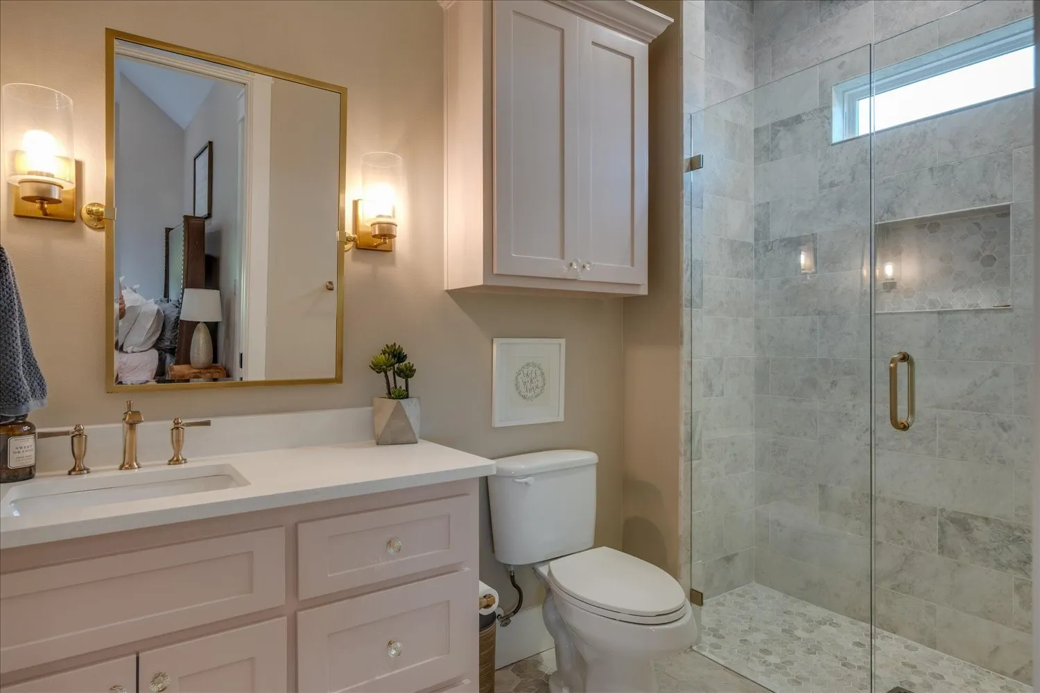 Vanity with quartz countertop and undermount sink, gold-tone fixtures, and dual wall sconces