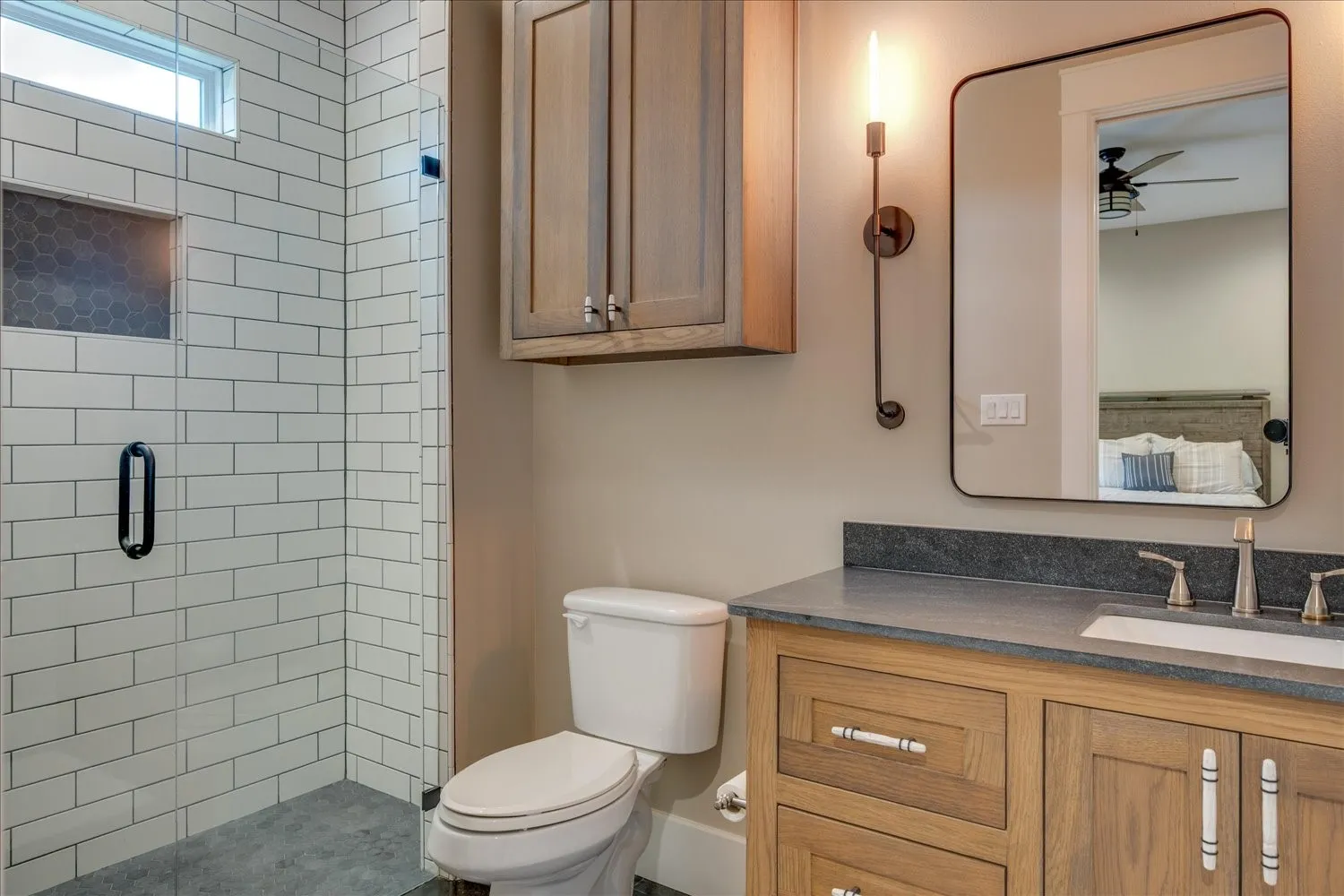 Glass-enclosed shower with white subway tile, hexagonal tile niche, and transom window