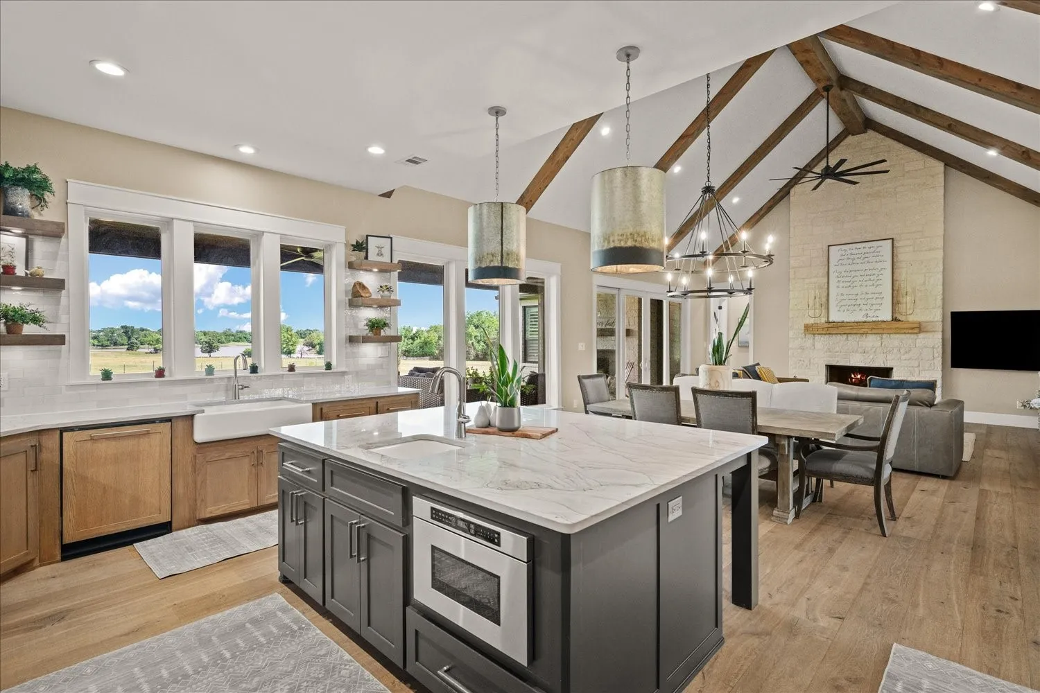 Spacious kitchen featuring a large central island with an integrated microwave, solid surface countertops, and a farmhouse sink
