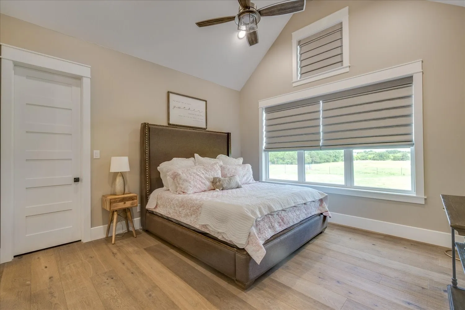 Vaulted ceiling, wood-finish flooring, ceiling fan, and window treatments