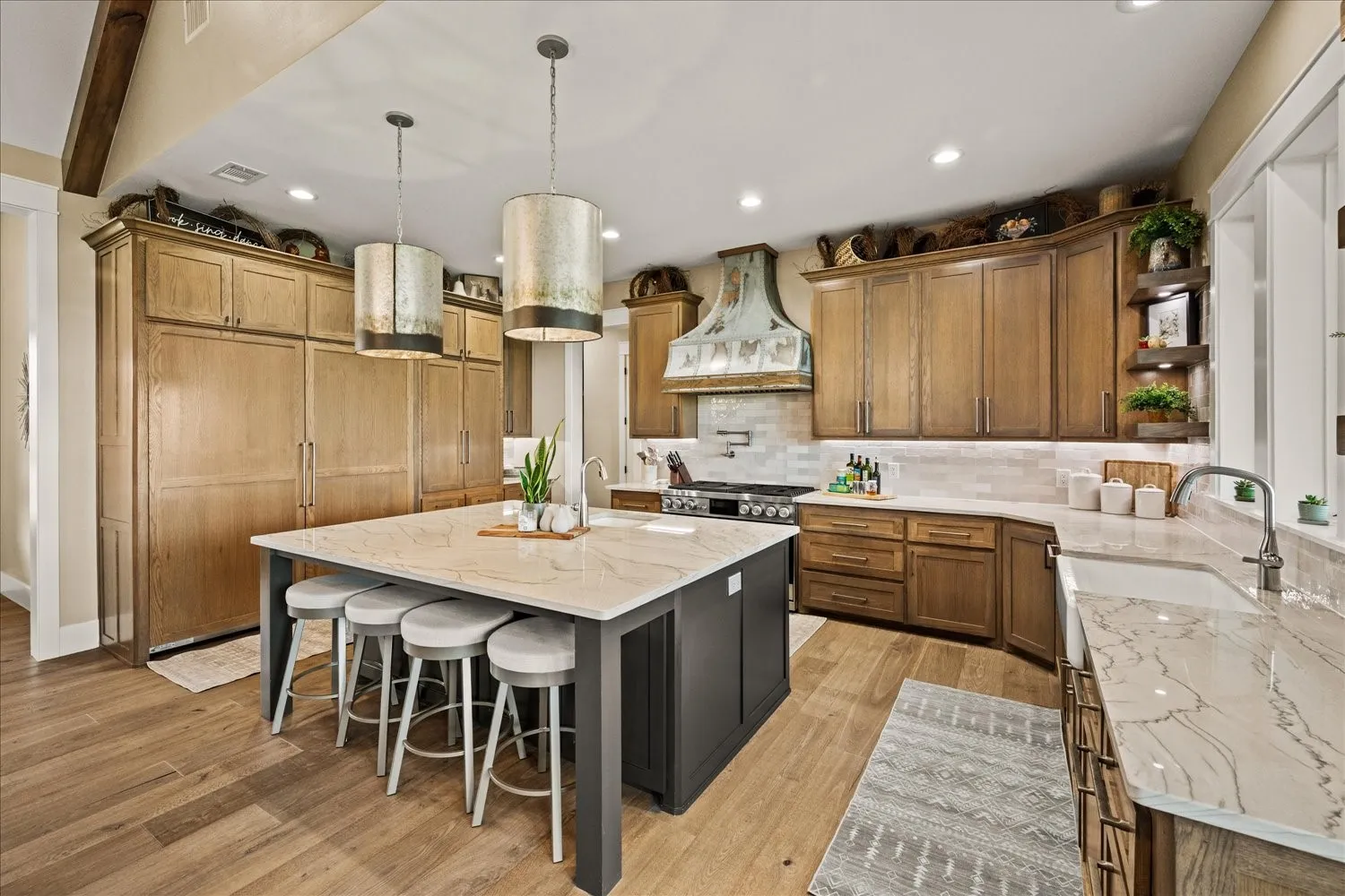 Gourmet kitchen with wood-finish flooring, a large center island, extensive cabinetry, light-toned countertops, and a farmhouse sink