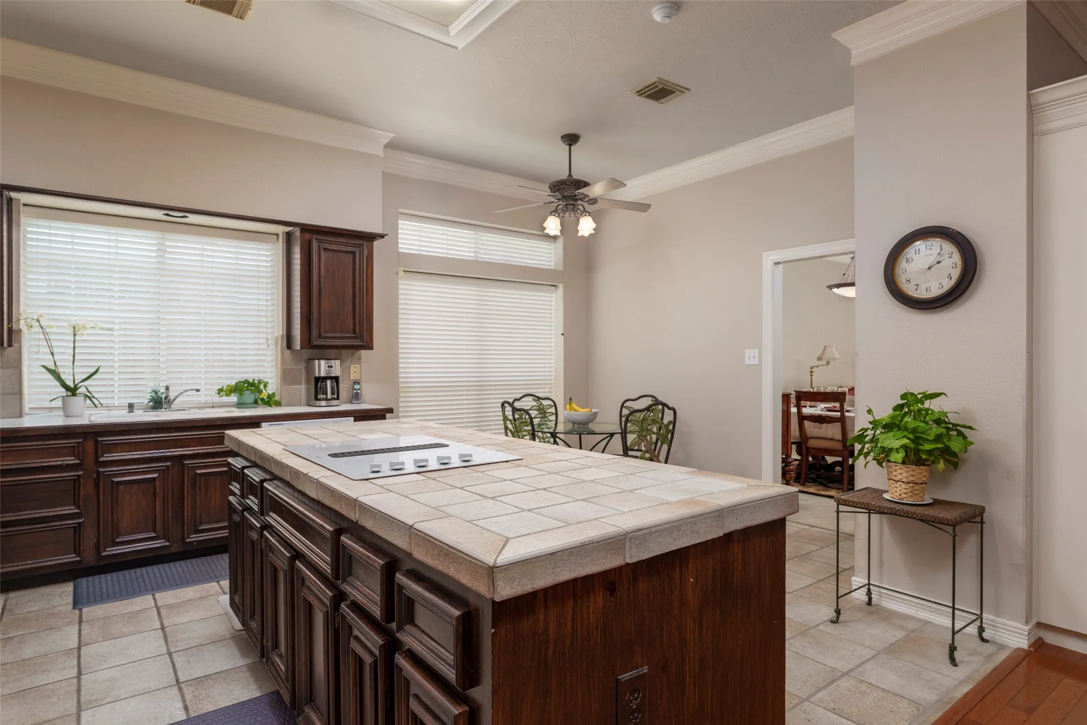 Kitchen featuring a tile-top island with a built-in cooktop, extensive wood cabinetry, and a tile floor