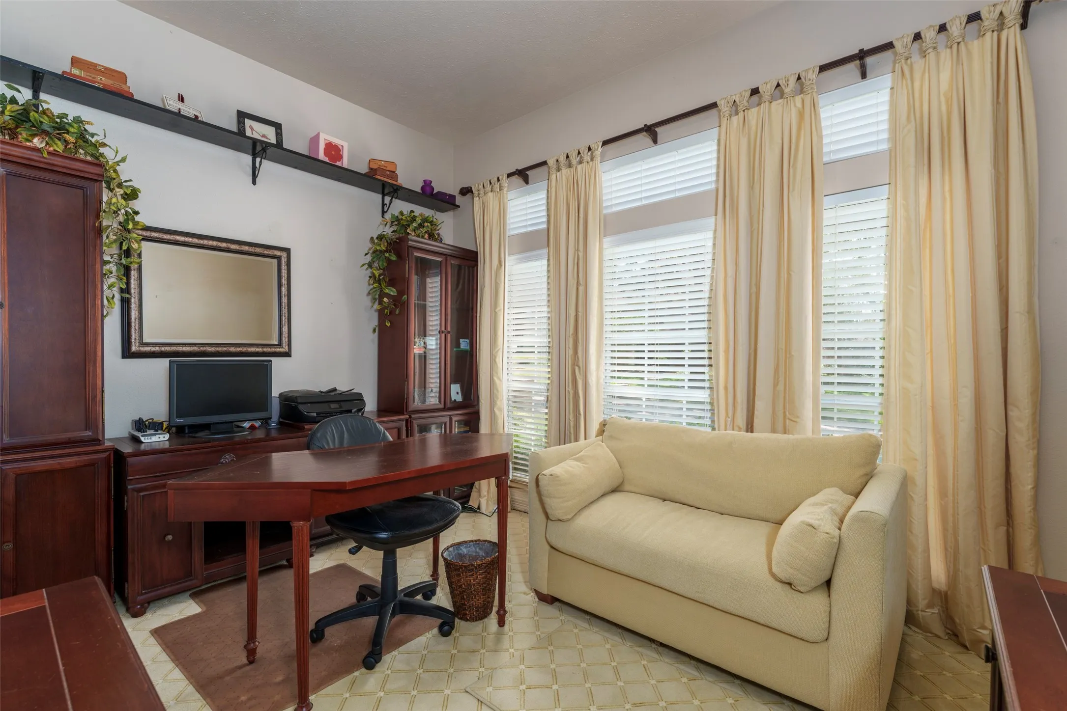 Tile flooring with a geometric pattern, multiple windows with horizontal blinds and drapery, and wall-mounted shelving