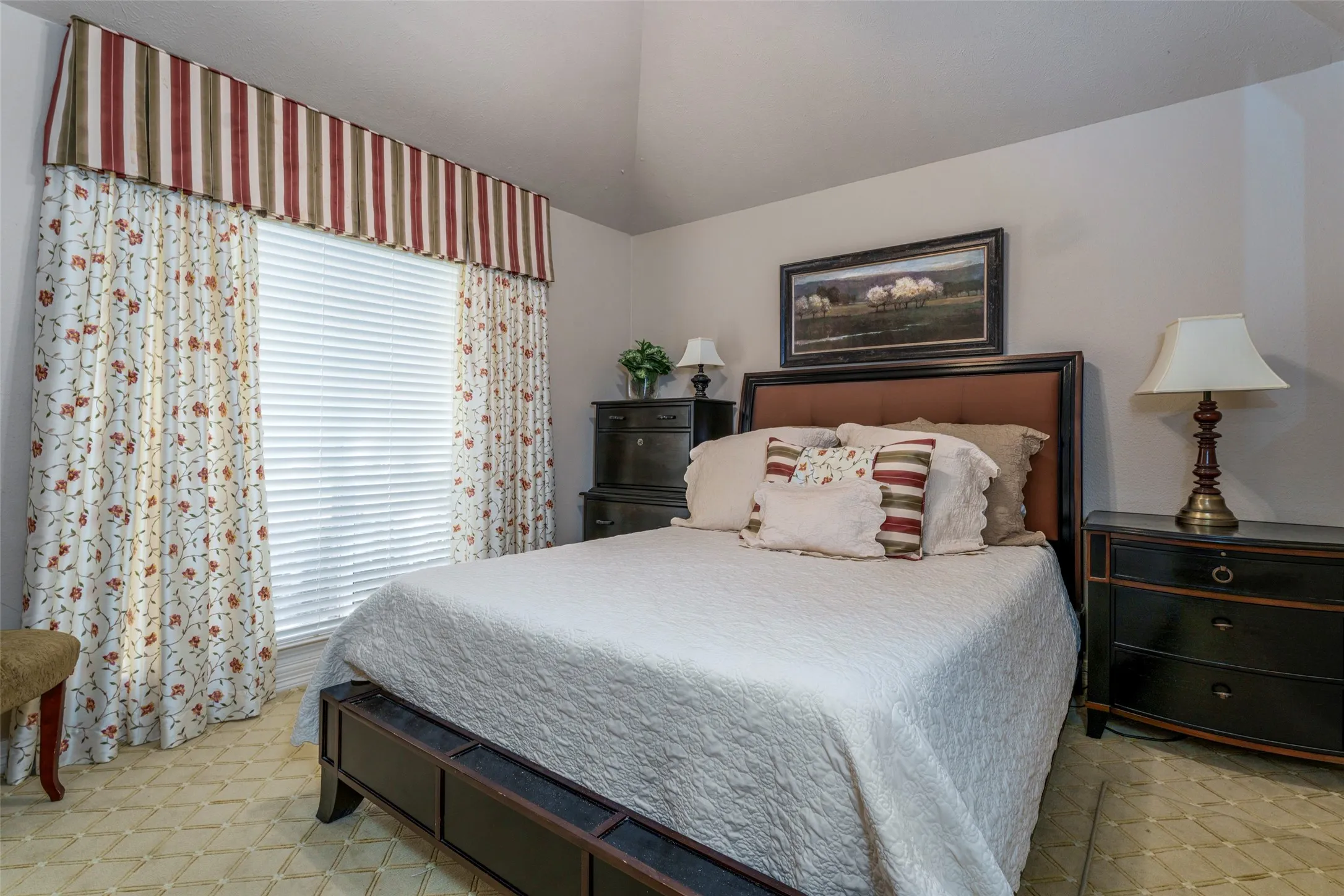 Vaulted ceiling, window with blinds, carpet flooring, wall-mounted artwork