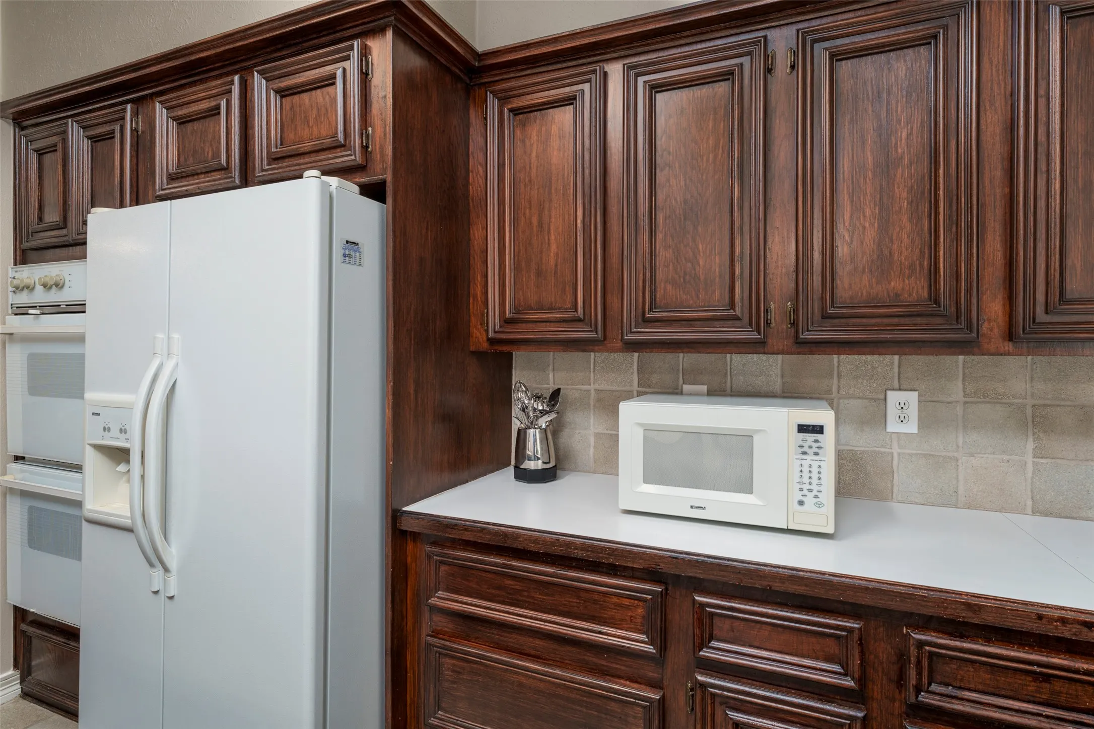Rich wood-finish cabinetry, solid surface countertops, and a tiled backsplash