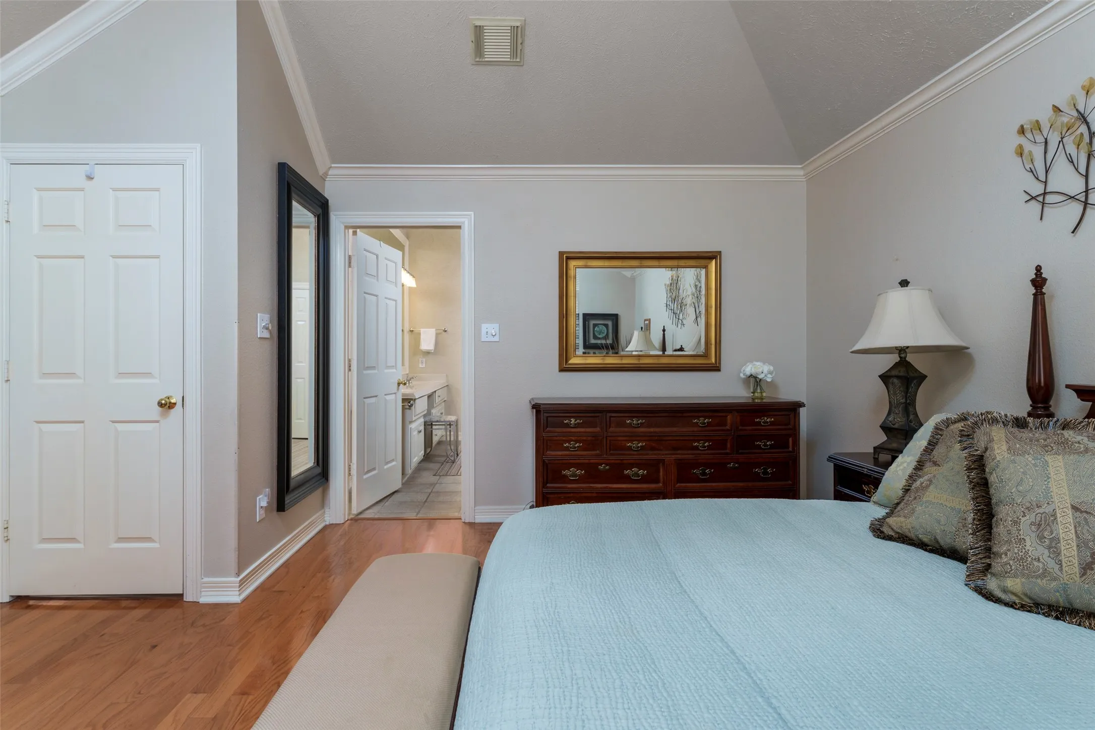Wood-finish flooring, vaulted ceiling, crown molding, double bi-fold closet doors, and attached full bathroom with tile flooring