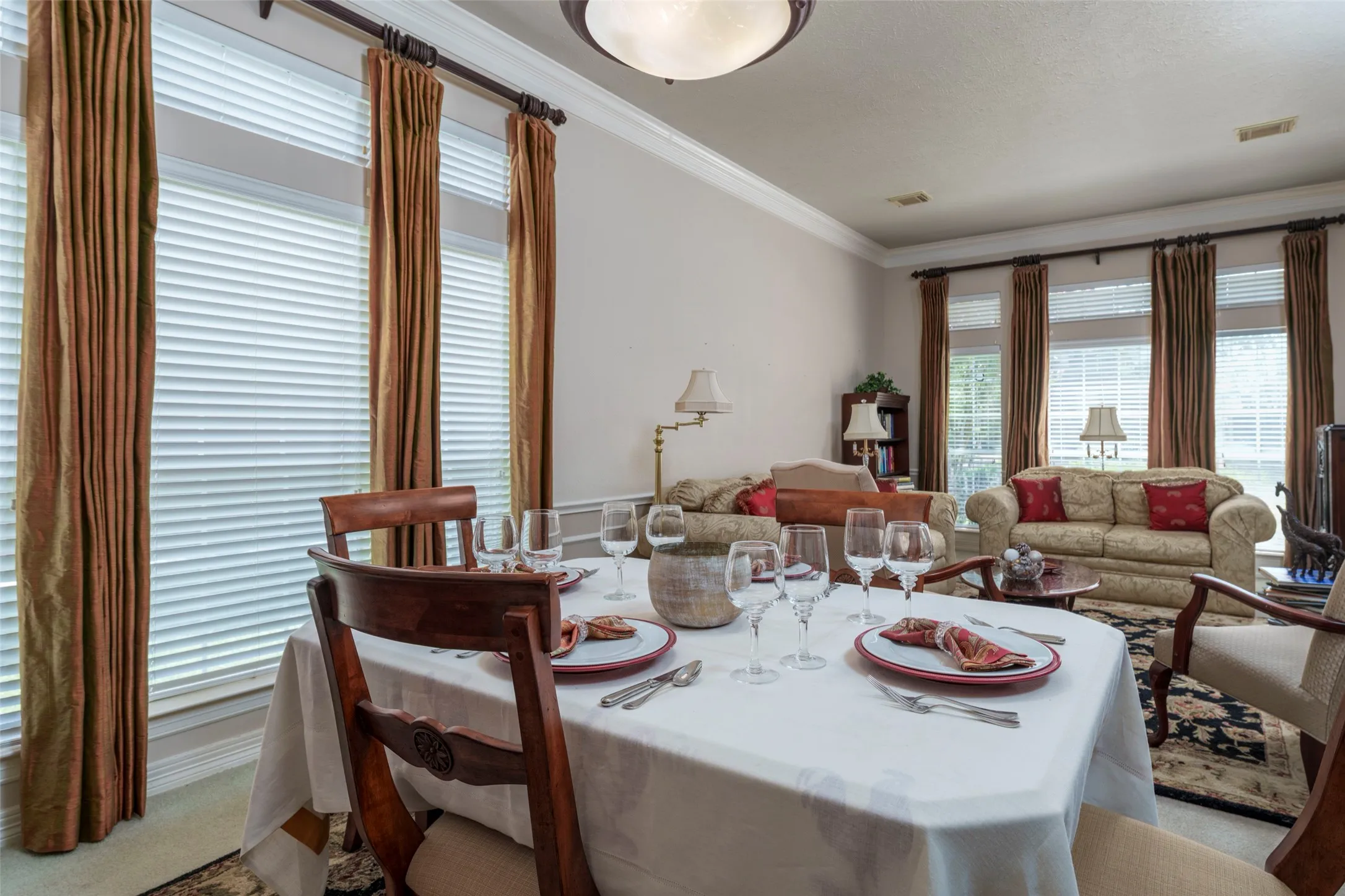 Crown molding, recessed lighting, and multiple windows with blinds and drapery