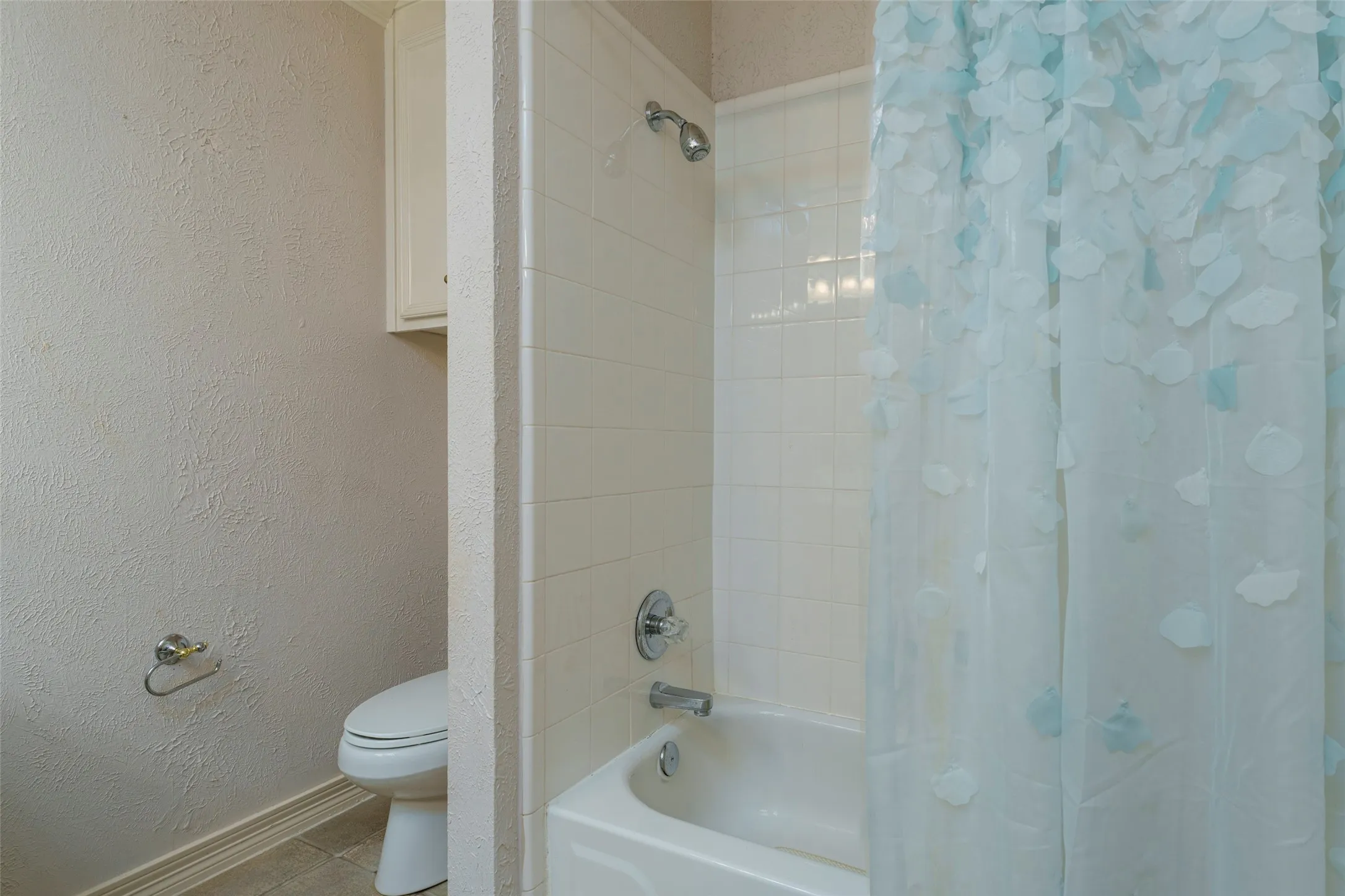 Integrated bathtub with a chrome shower fixture, white subway tile surround, and a built-in wall cabinet